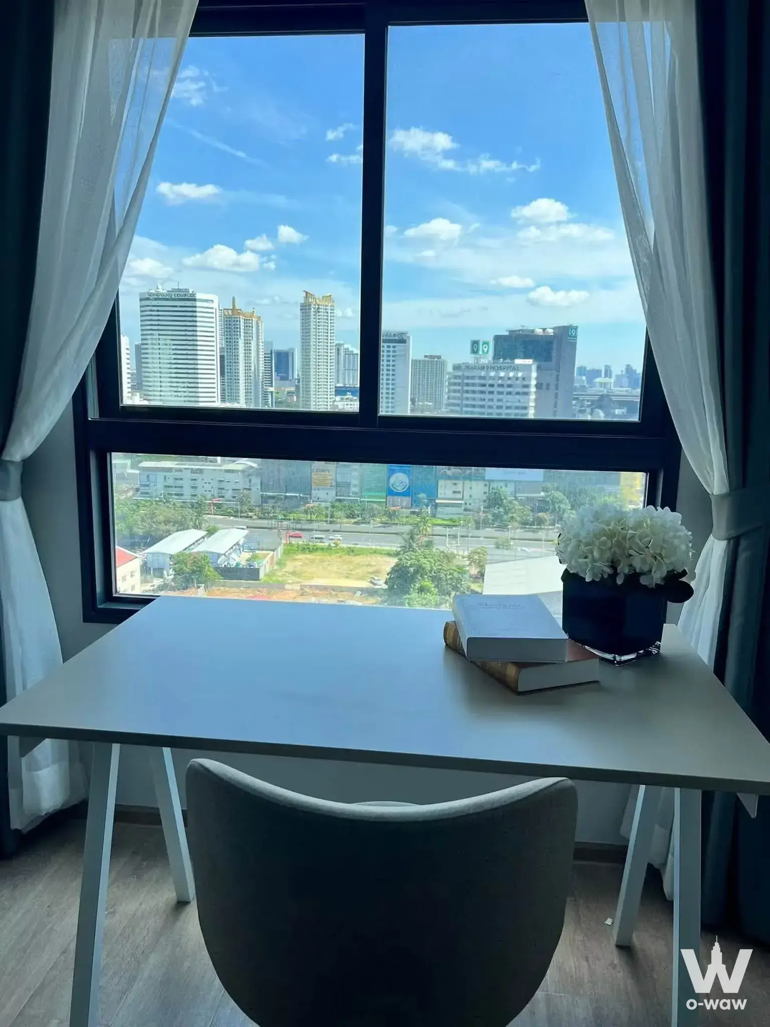 Dining nook in an IDEO Rama 9 Asoke 1-bed condo with a grey chair and floor-to-ceiling city views