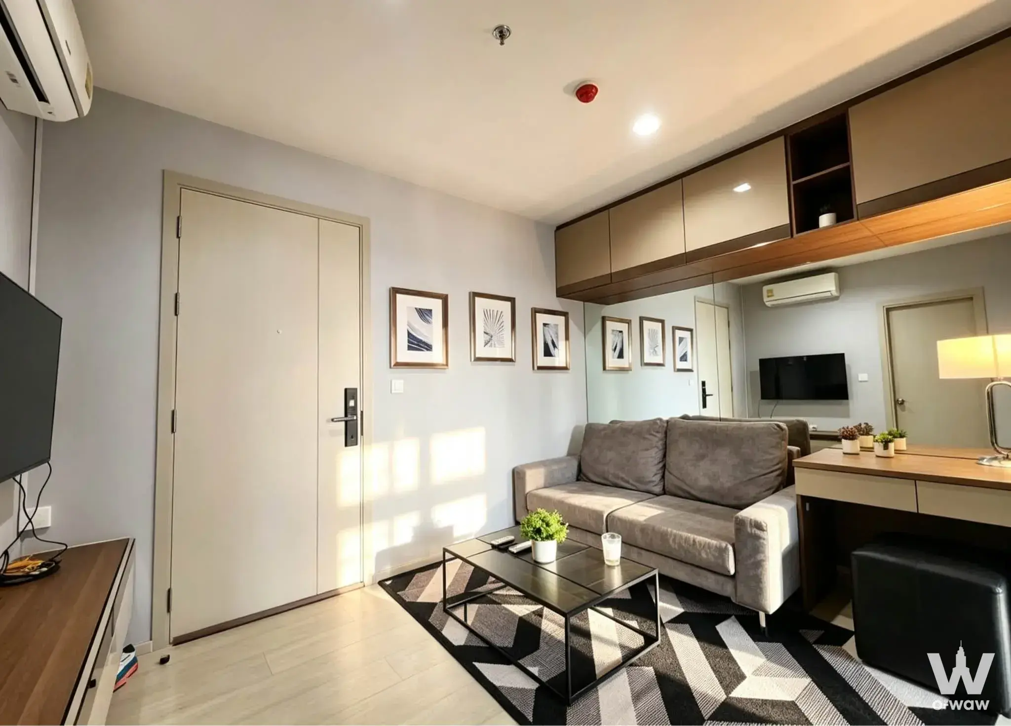 Tidy living room in a Life Sukhumvit 48 1-bed other for rent, with grey sofa, abstract art, and natural sunlight