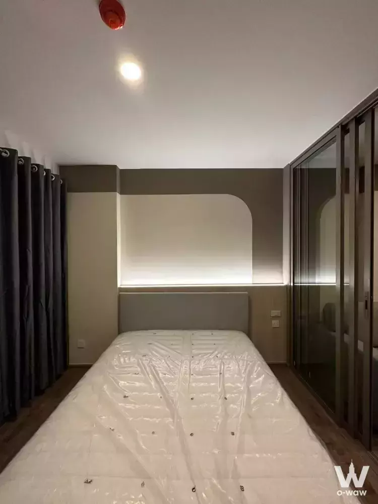 Bedroom in an Aspire Pinklao condo featuring a two-tone wall and glass wardrobe