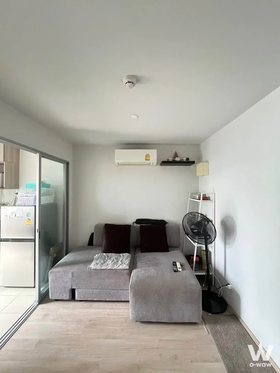 1-bed condo for sale in Elio Del Moss Phaholyothin featuring grey sectional sofa and open kitchen view
