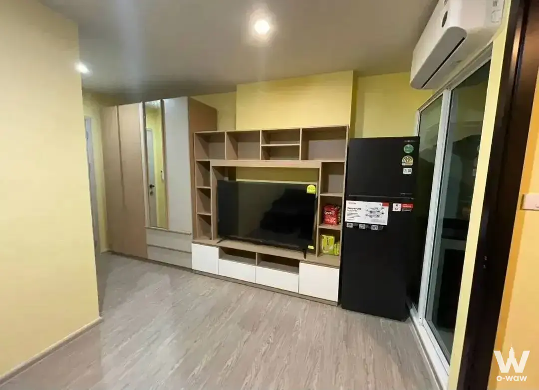 Empty living room in Regent Home Bangna condo featuring light oak built-ins and a sliding glass door to the balcony