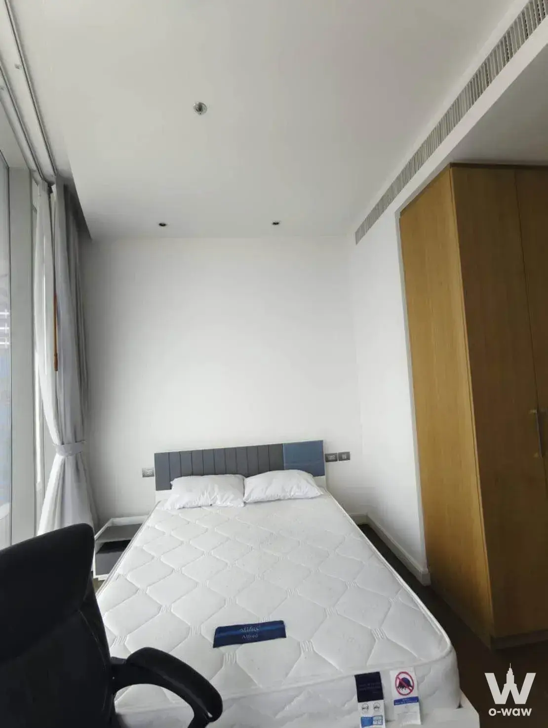 Tidy bedroom with grey upholstered headboard and light wood wardrobe in the Magnolias Ratchadamri condo