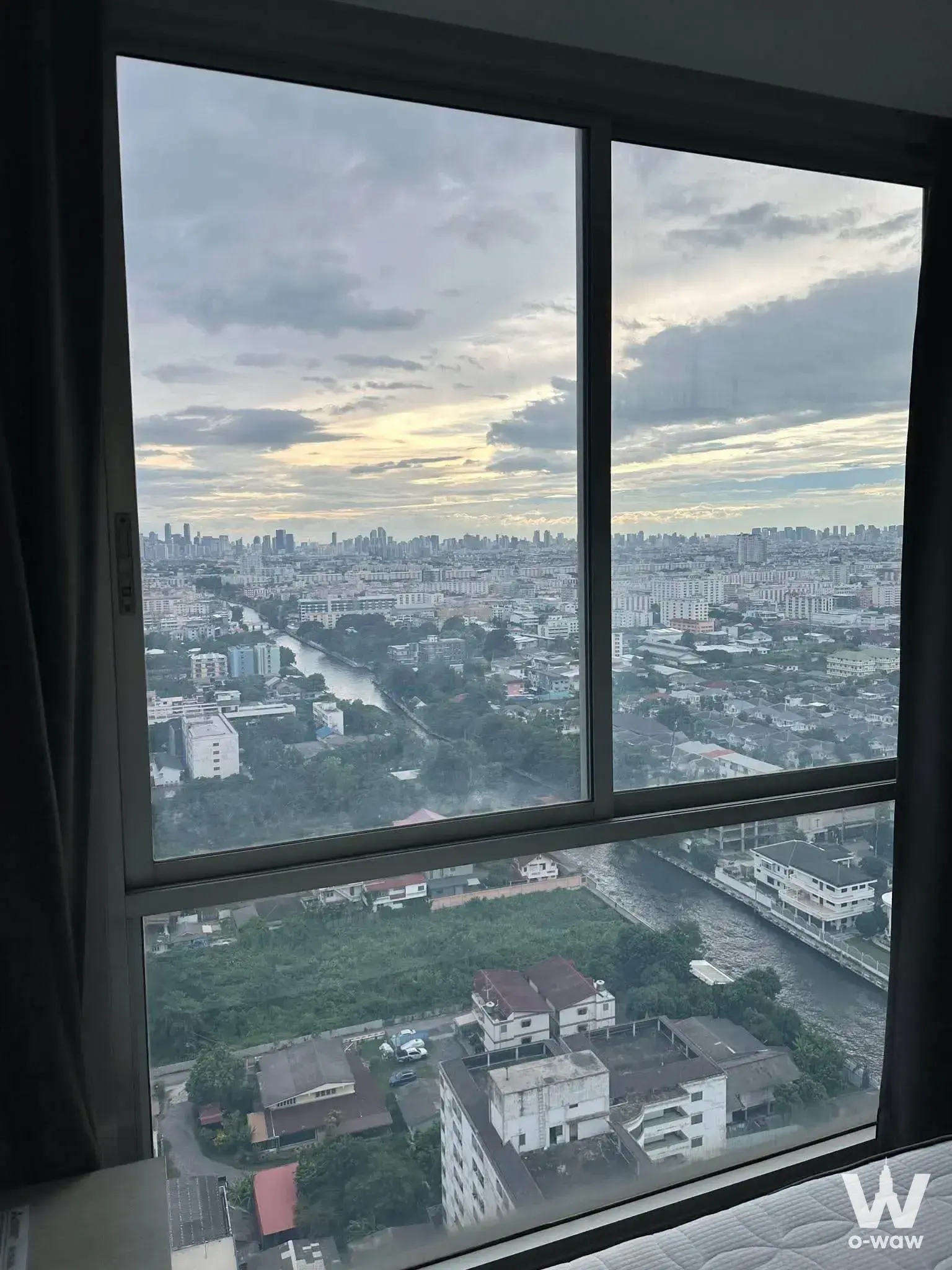 High-floor city view from a 1-bed condo in Chewathai Ramkhamhaeng showing skyline and river at sunset
