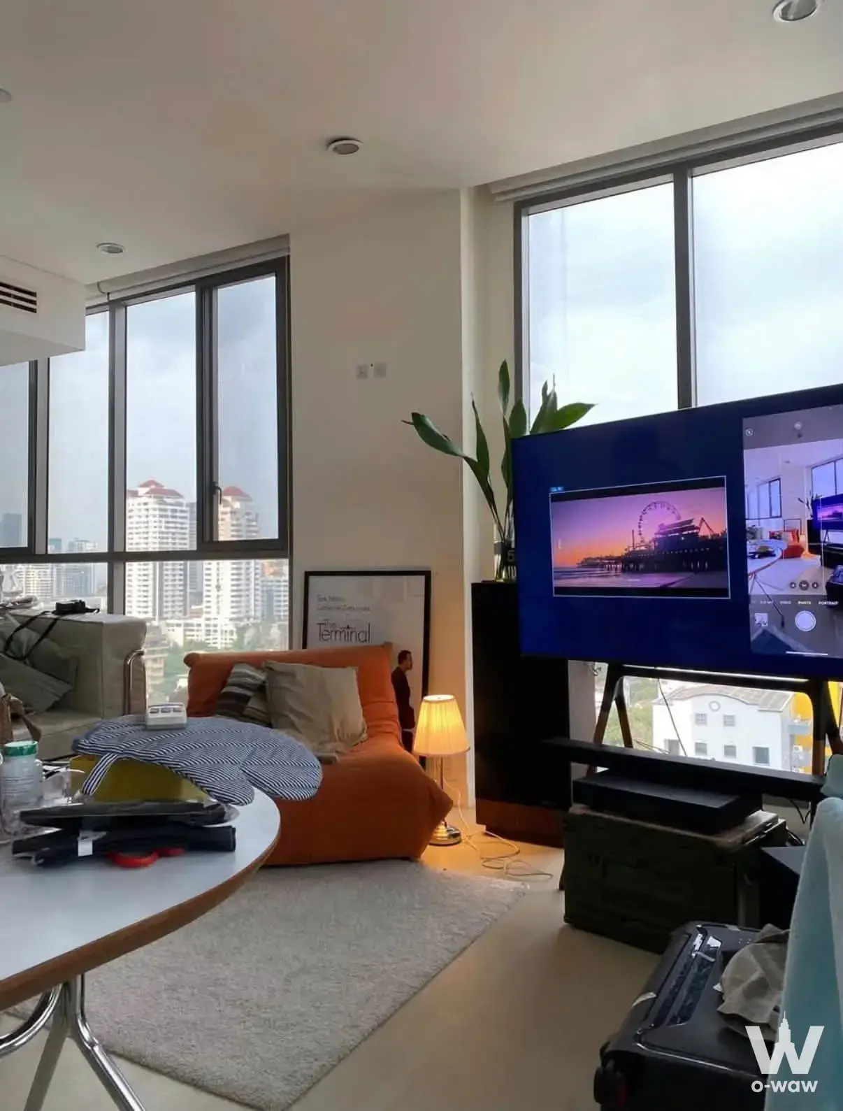 Living room in AEQUA Residence Sukhumvit 49 condo with city skyline view, orange beanbag, and large TV
