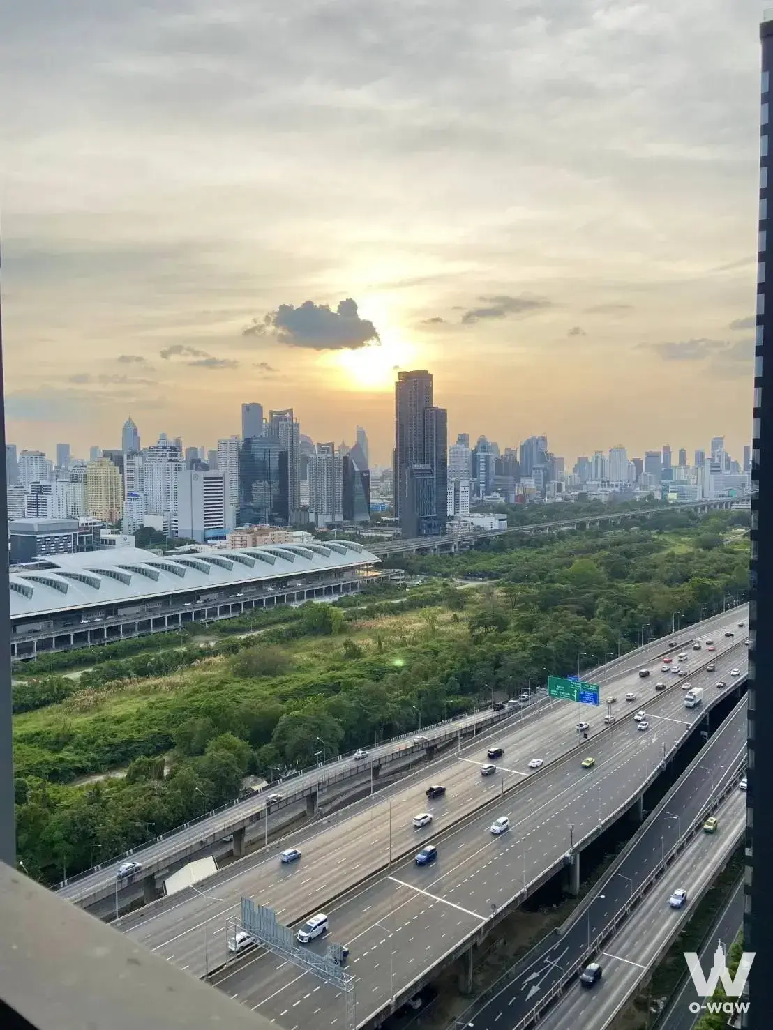 High-floor Chewathai Residence Asoke balcony view of highway, park, and city skyline