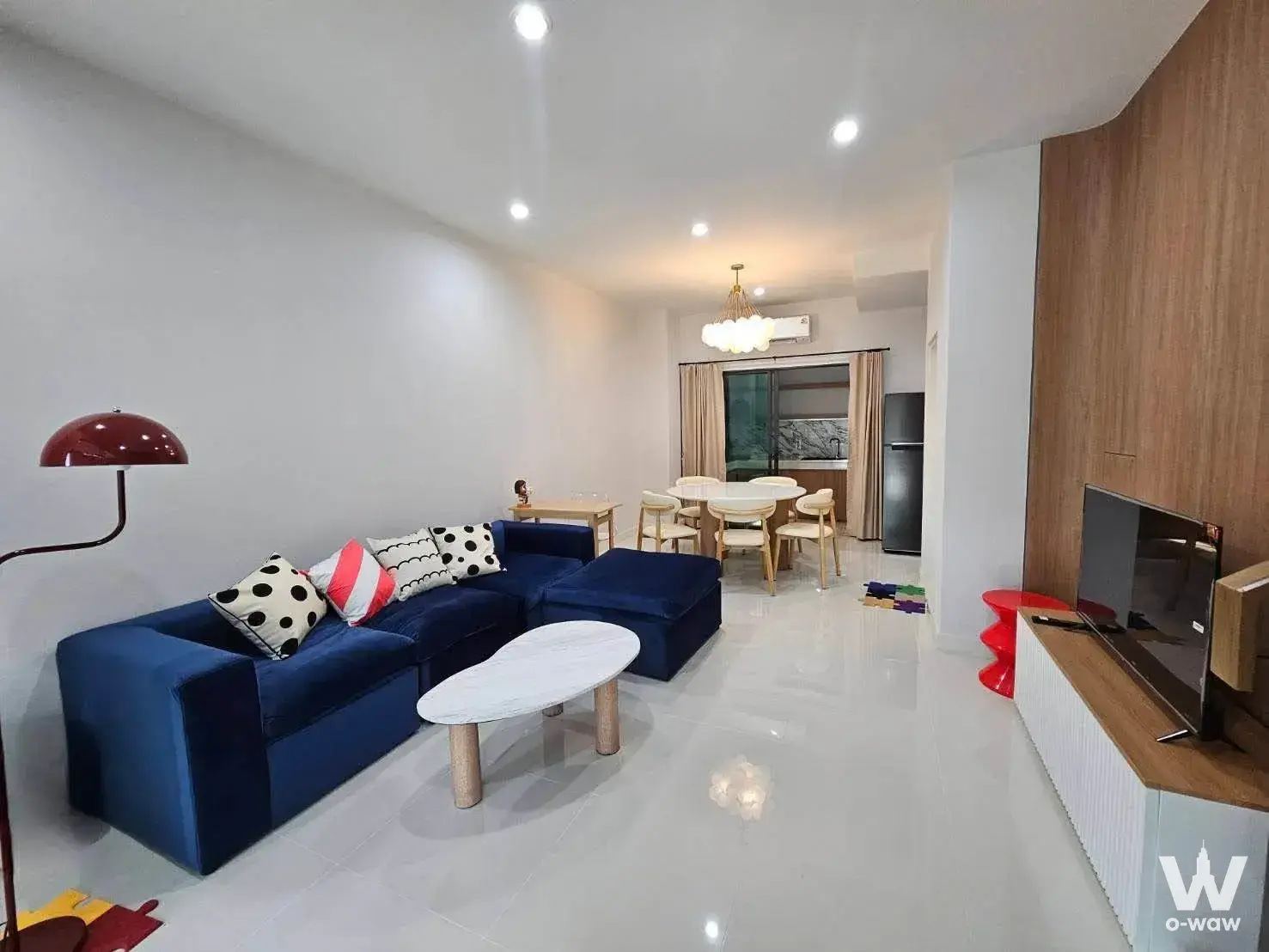 Open-plan living room in a Rama 9 townhouse featuring a deep-blue velvet sectional and marble coffee table