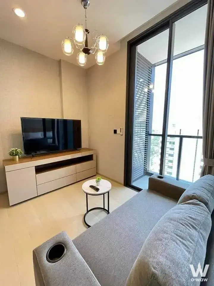 Bright living room in a 1-bed THE EXTRO Phayathai-Rangnam rental with grey sofa and balcony access