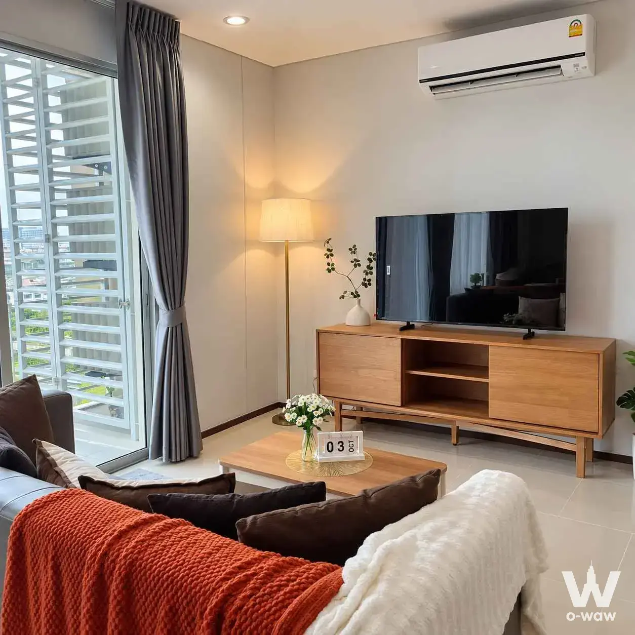Modern living room in a Villa Sathorn condo featuring a dark-grey sofa and city view