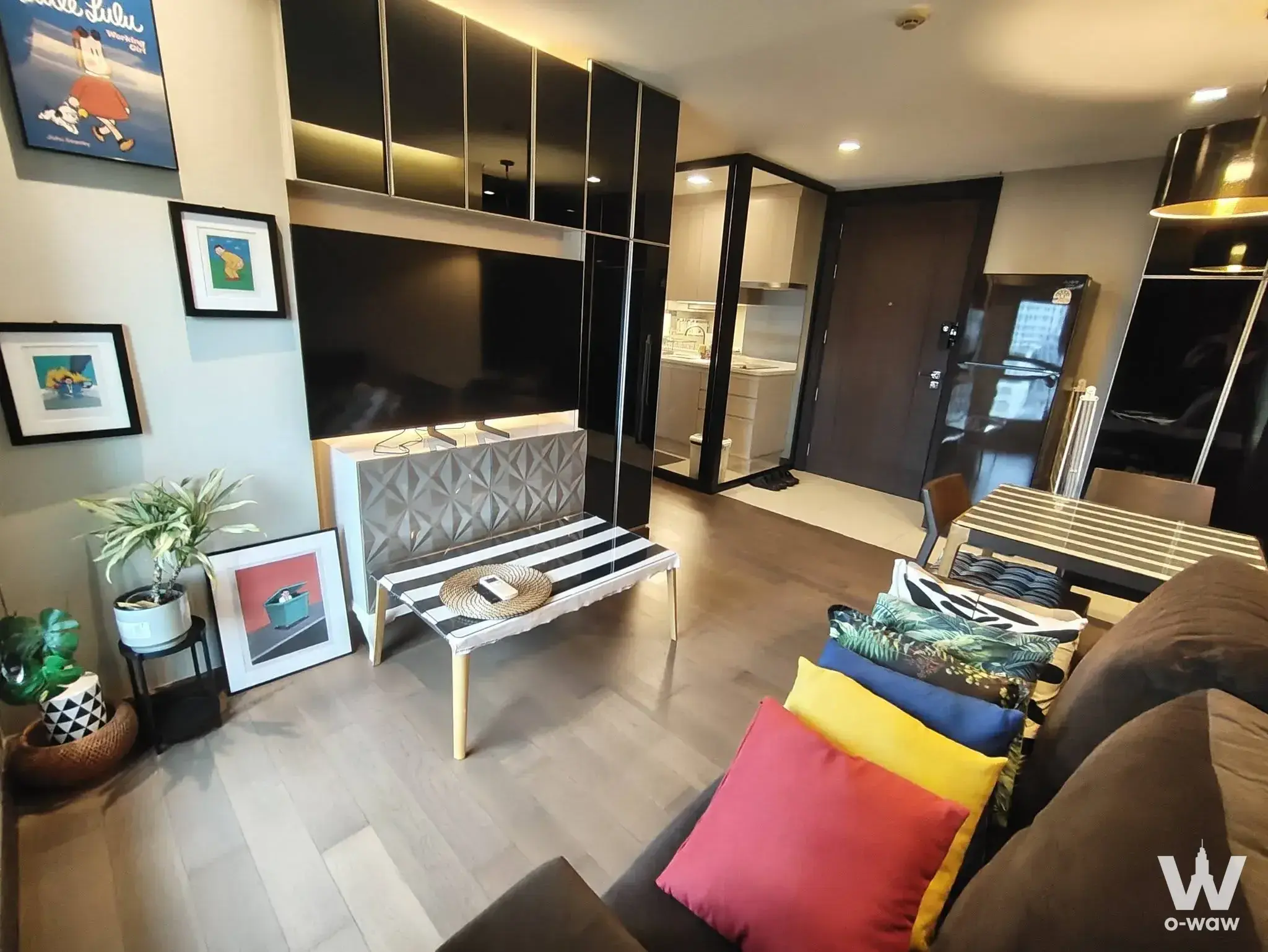 Open-plan living room with TV and dining area in a 1-bed condo for rent in Tidy Thonglor