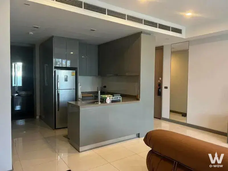 Open-plan kitchen with glossy grey cabinets, central island, and cream tile floors in an M Silom condo rental