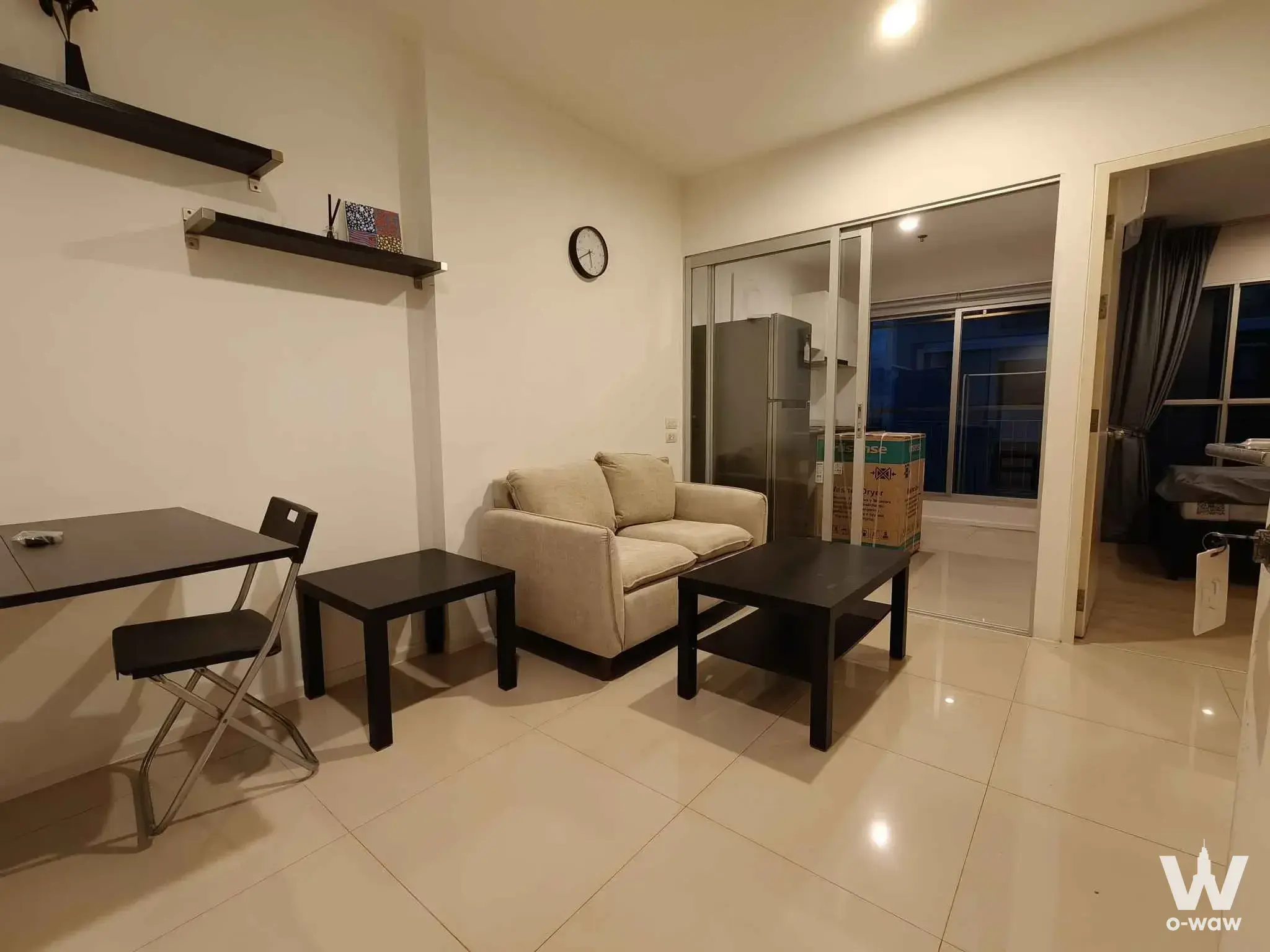 Cream sofa in an Aspire Sukhumvit 48 studio with dark wood furniture and sliding glass partition