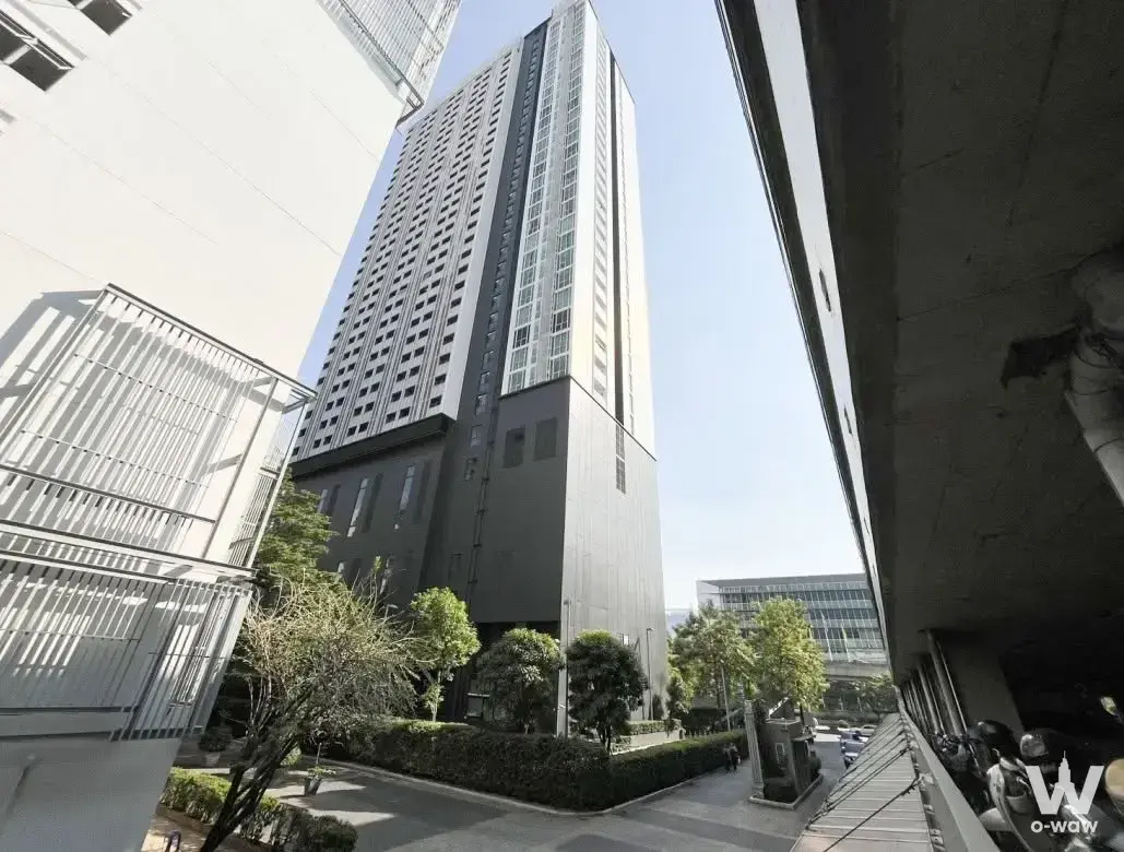 Exterior of A Space ID Asok-Ratchada condo showing the modern high-rise tower facade against a blue sky