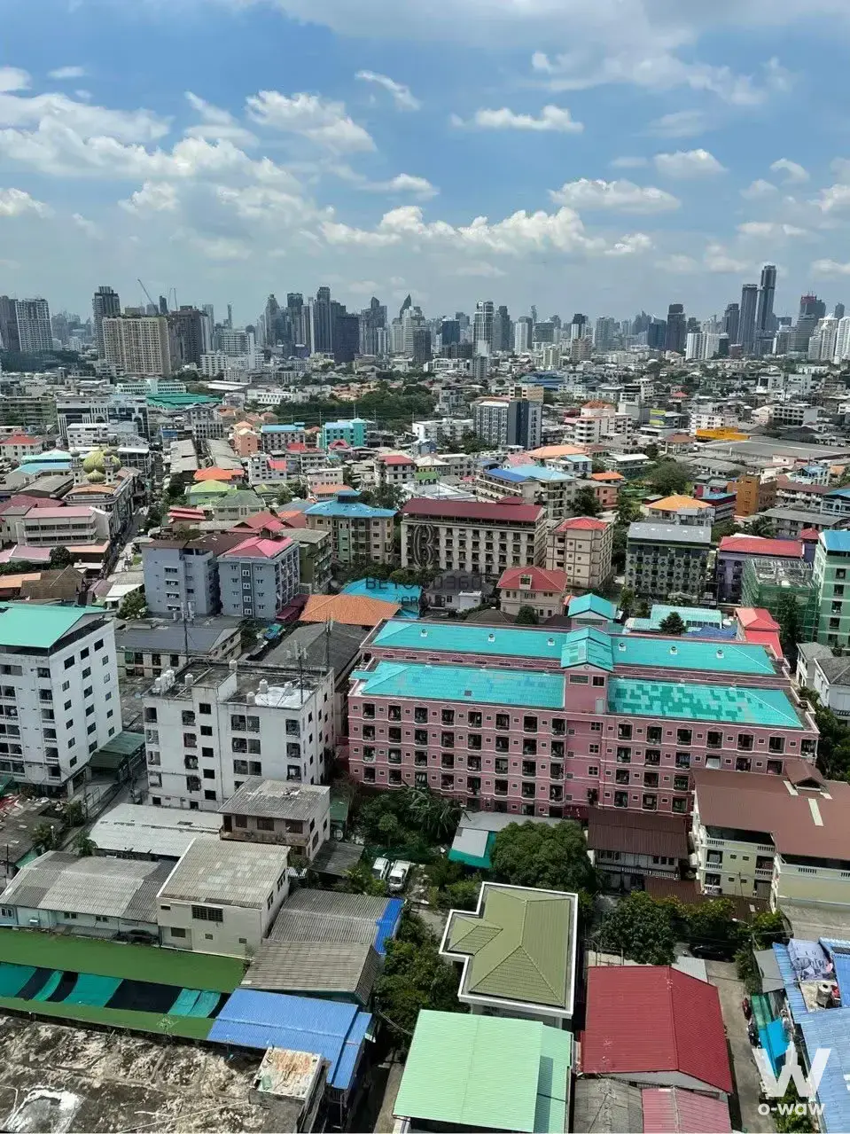 High-floor city view from a 2-bed NIA condo by Sansiri showing dense skyline and pink building