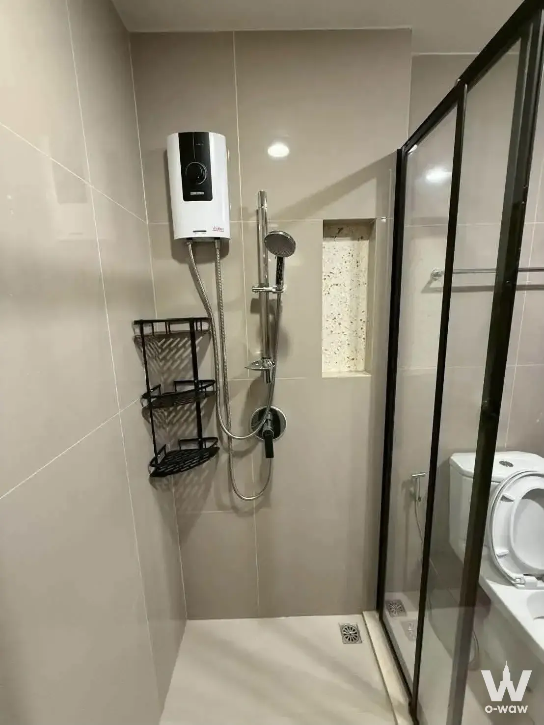 Compact bathroom in an XT Huai Khwang sale listing featuring beige tiles and a glass-enclosed shower
