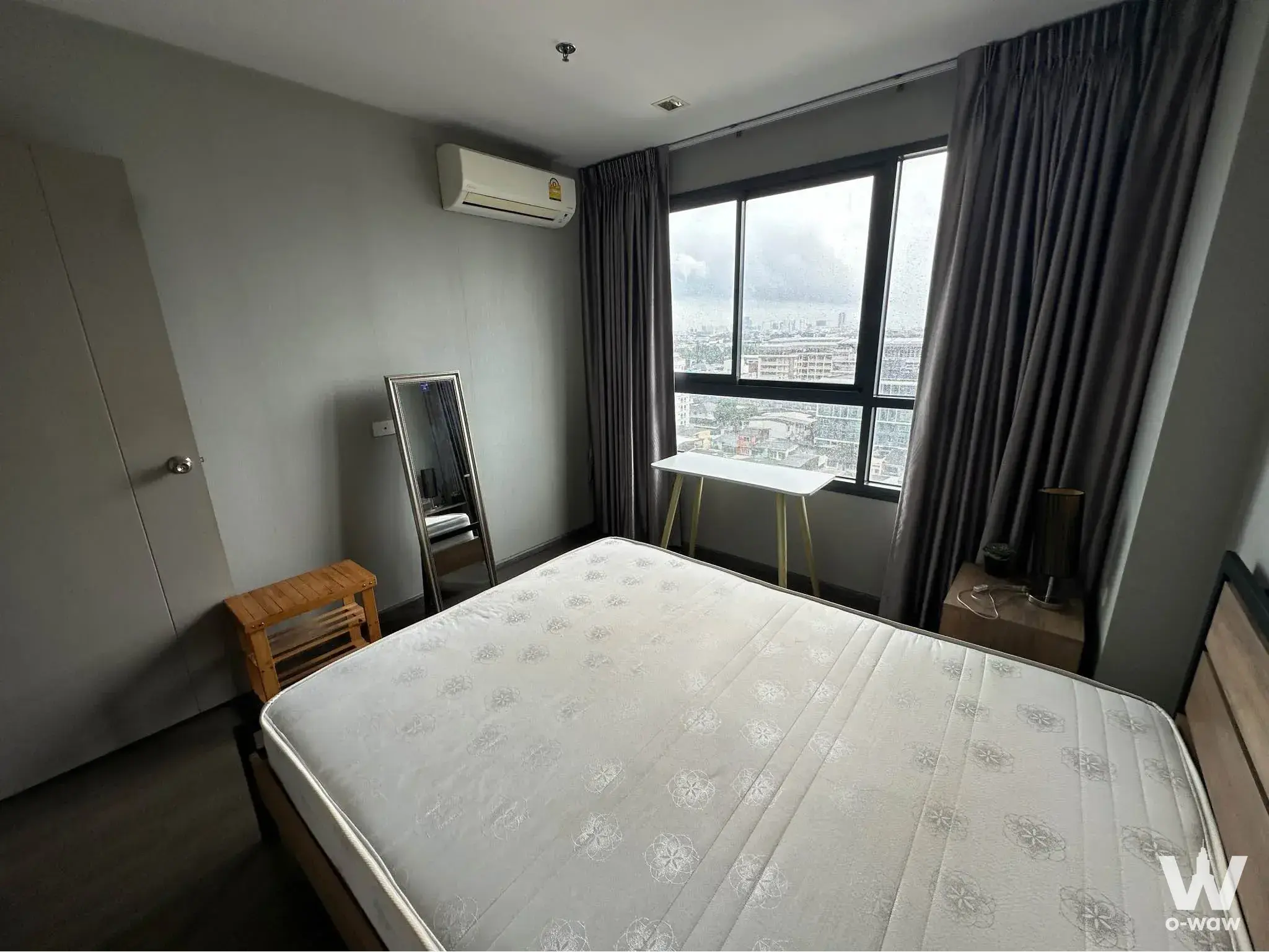Ideo Sukhumvit 93 furnished bedroom with city view window, desk, and minimalist grey tones