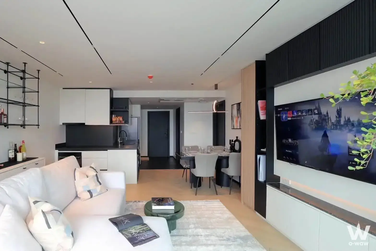 Lake Avenue 1-bed condo living area with white sofa, smart TV on slat wall, and open-plan kitchen with black accents