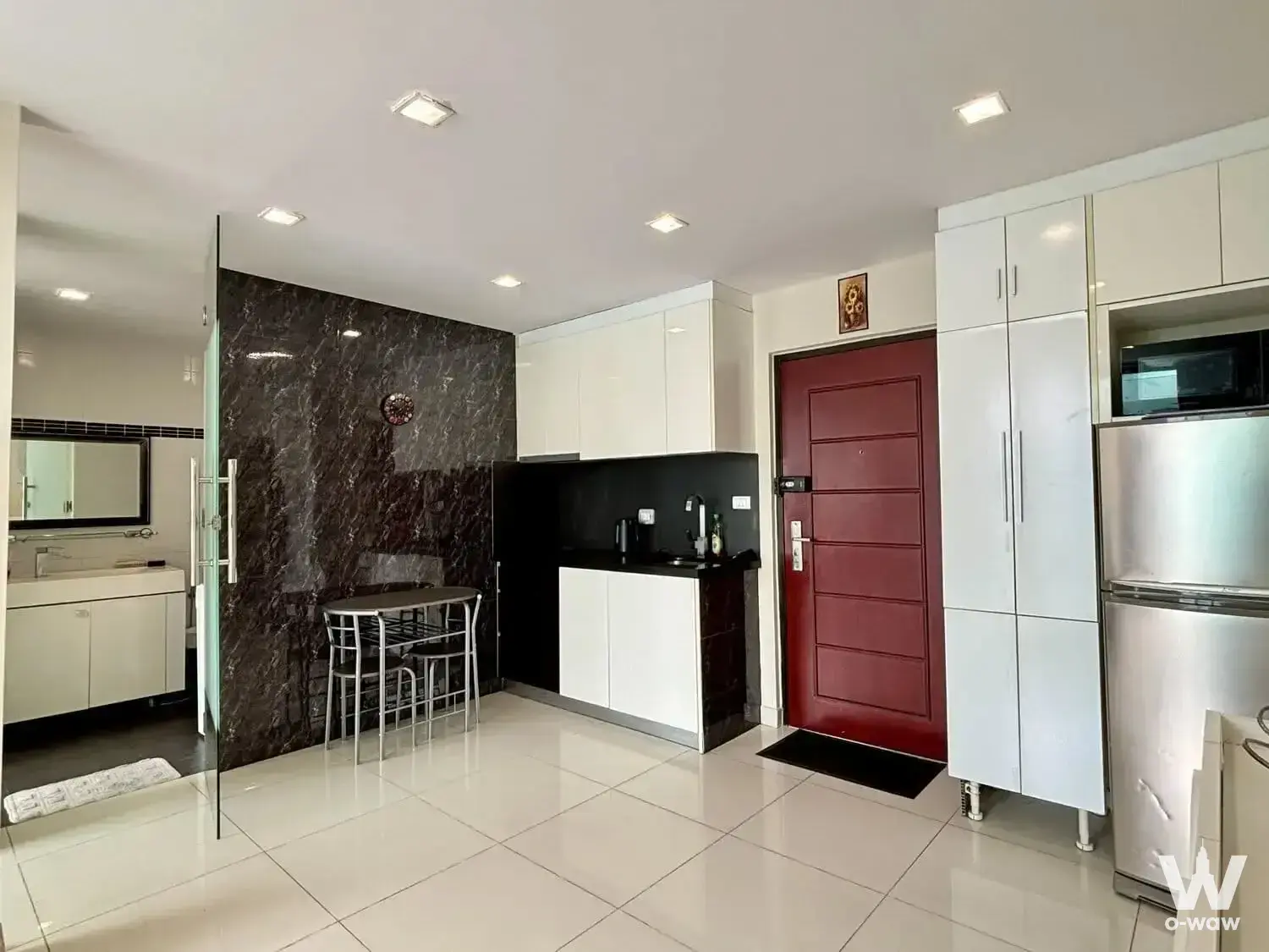 Open-plan 1-bed condo for sale in Park Royal 3 has a marble feature wall, kitchenette, and glass bathroom partition