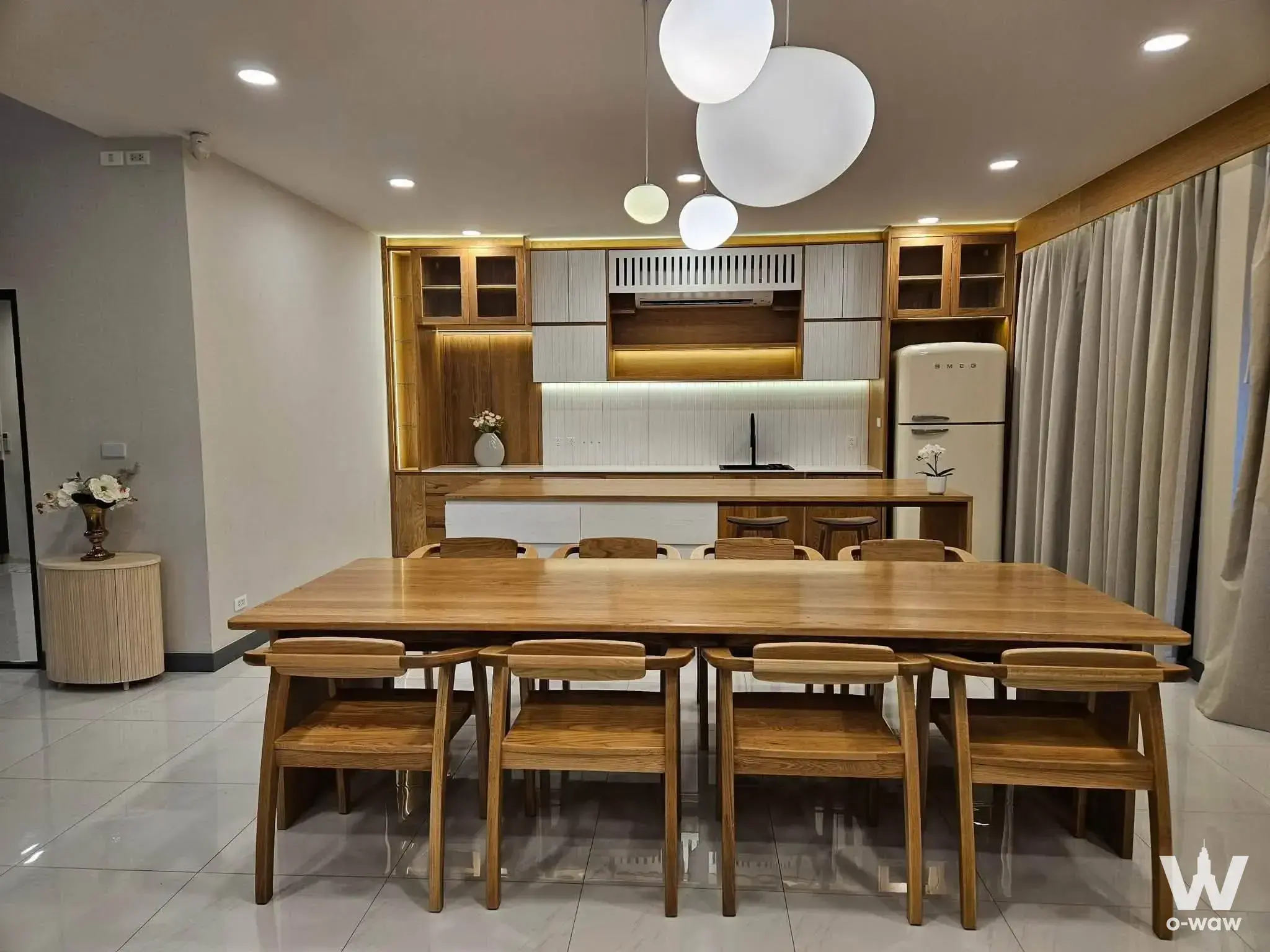 This open-plan dining kitchen has a wood table and retro refrigerator in a 5-bed house for sale in The City Bangna