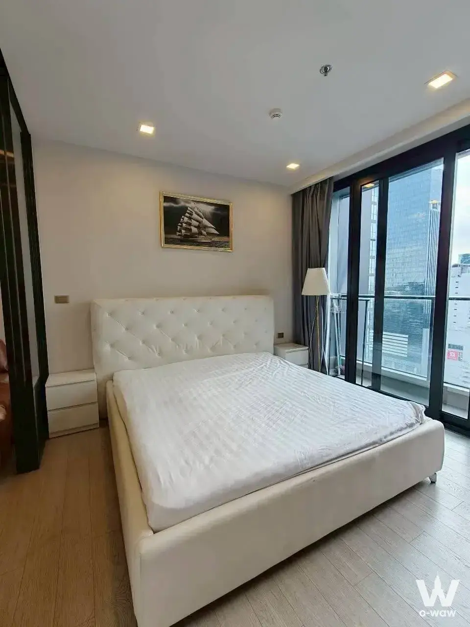 Master bedroom in a 1-bed condo for sale in One9Five Asoke - Rama 9 with a tufted bed, ship painting, and city view