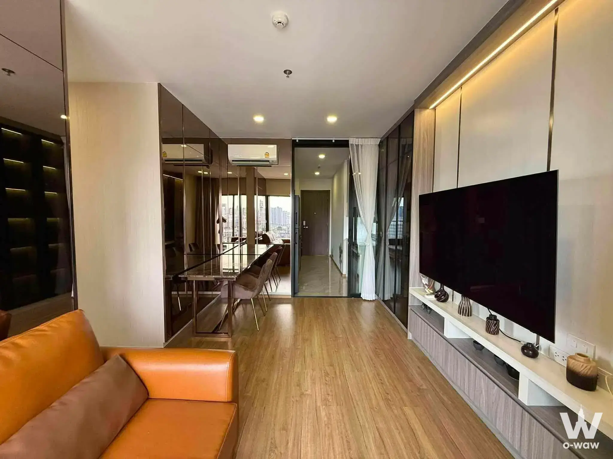 Cloud Thonglor-Phetchaburi 2-bed condo living room featuring orange leather sofa and glass dining table