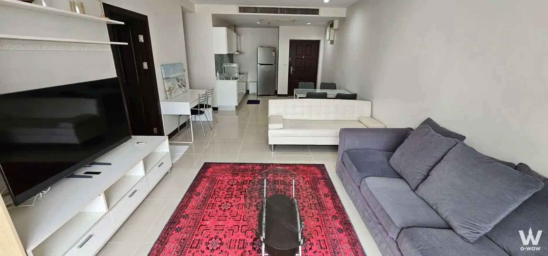 Furnished 2-bed condo living room in The Prime 11 featuring a red rug and modern seating