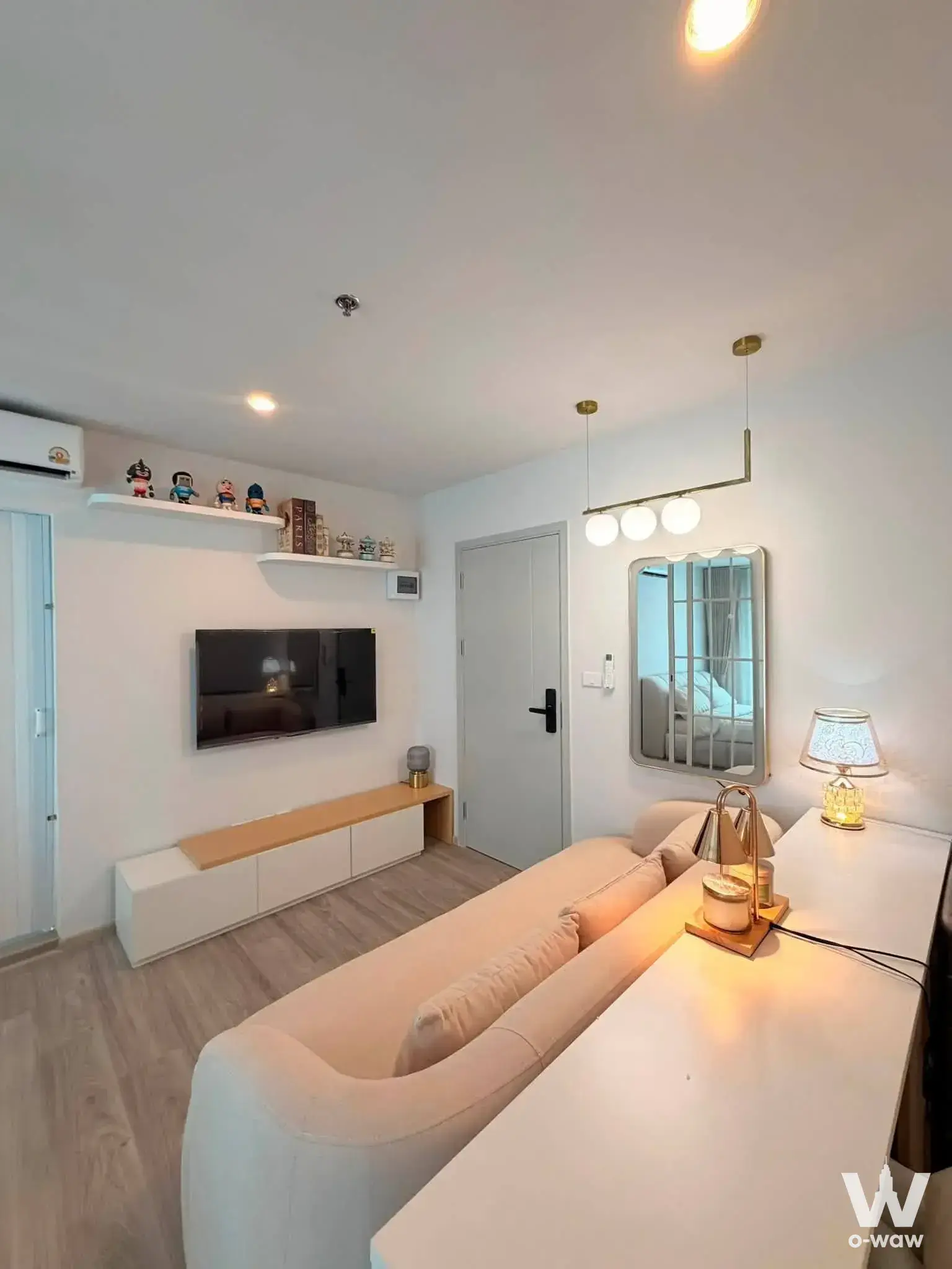 Living room in a 2-bed Ideo O2 rental with a curved beige sofa and wall-mounted flat-screen TV