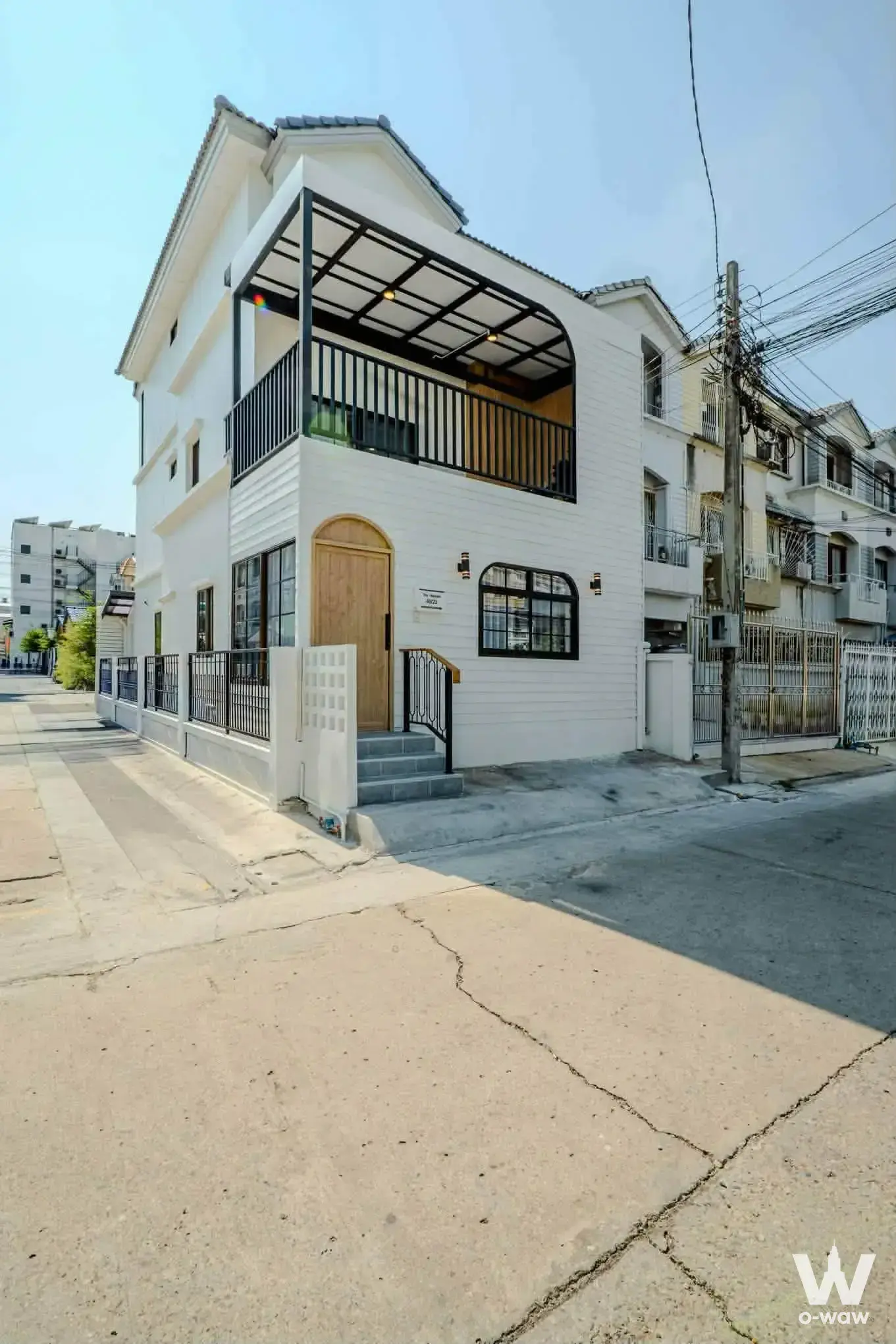 4-bed white townhouse for sale in Baan Klang Muang Rama 9 has arched door, balcony canopy and black railings