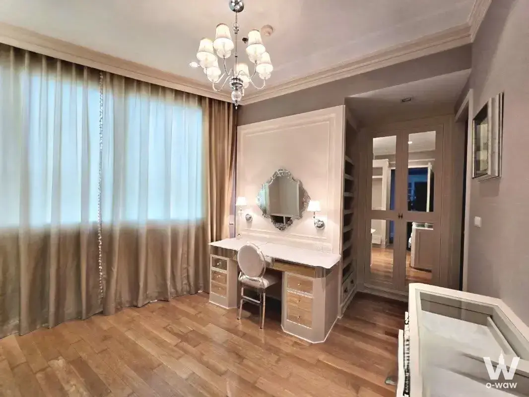 The bedroom dressing corner in a 3-bed Millennium Residence rental has a chandelier, vanity desk, and mirror