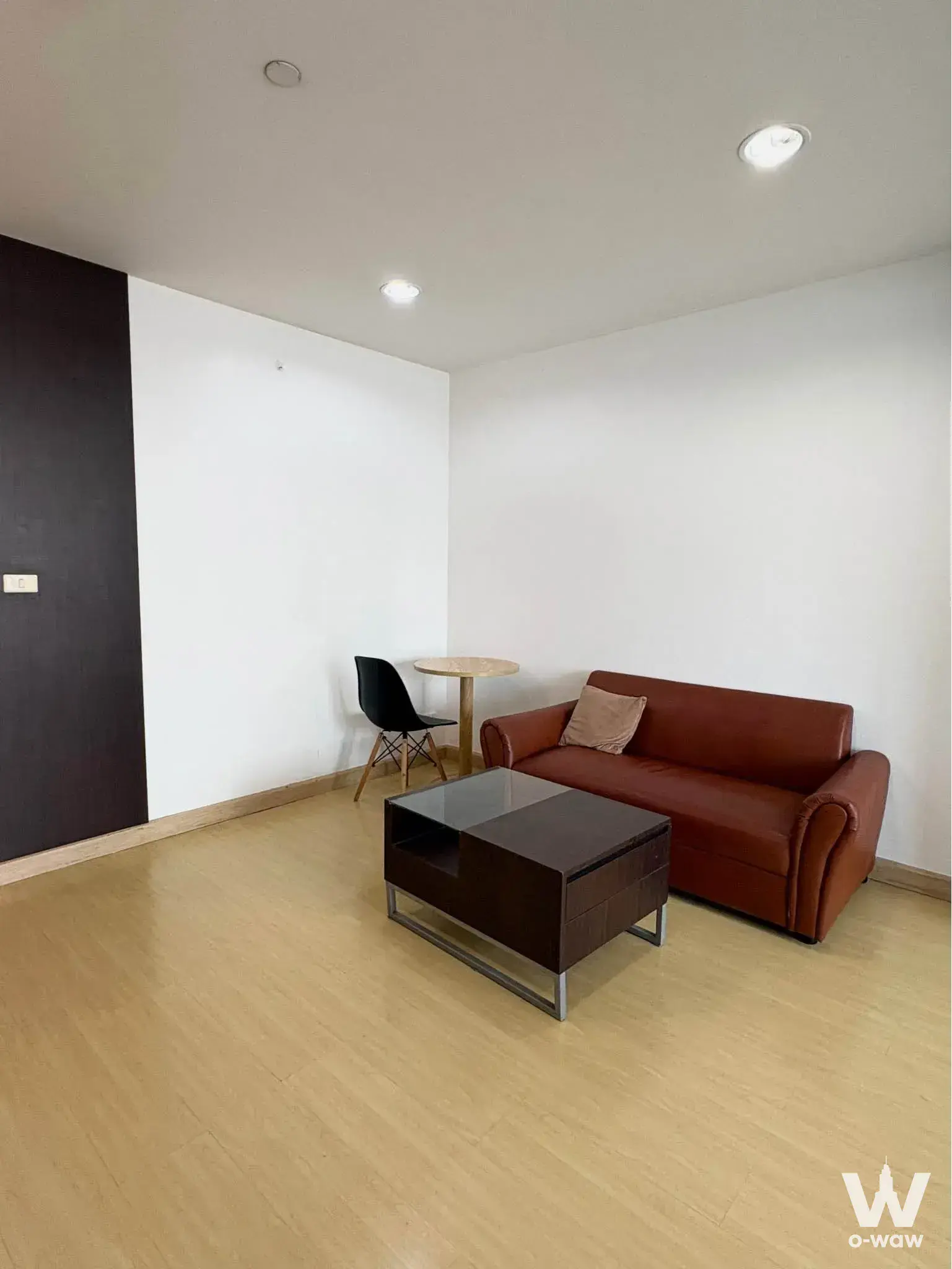 Modern living room in a 1-bed condo at The Station featuring a reddish-brown leather sofa and dark wood coffee table