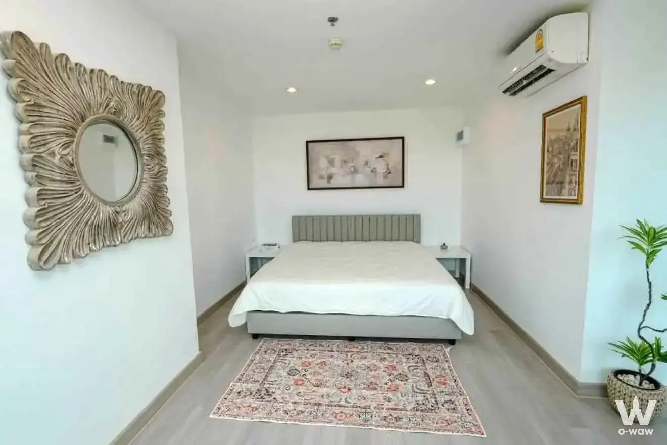 1-bed condo for sale in Lumpini Seaview Jomtien bedroom with grey tufted headboard and sunburst mirror