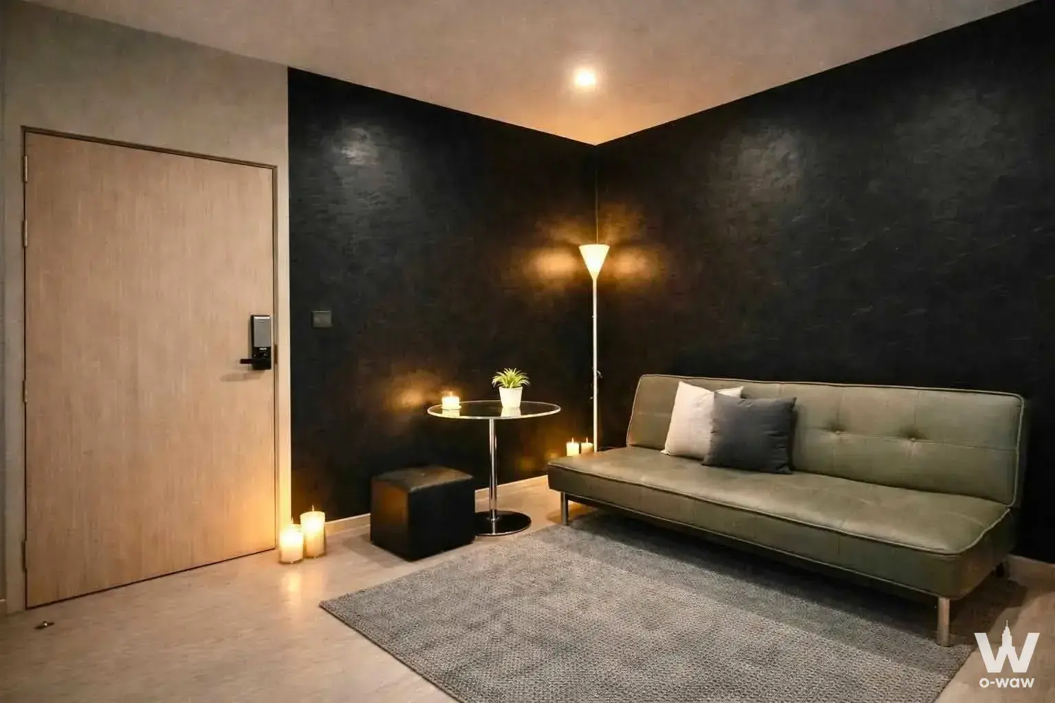 Moody living room with sage-green sofa and charcoal wall in this 1-bed condo for rent at M Thonglor 10
