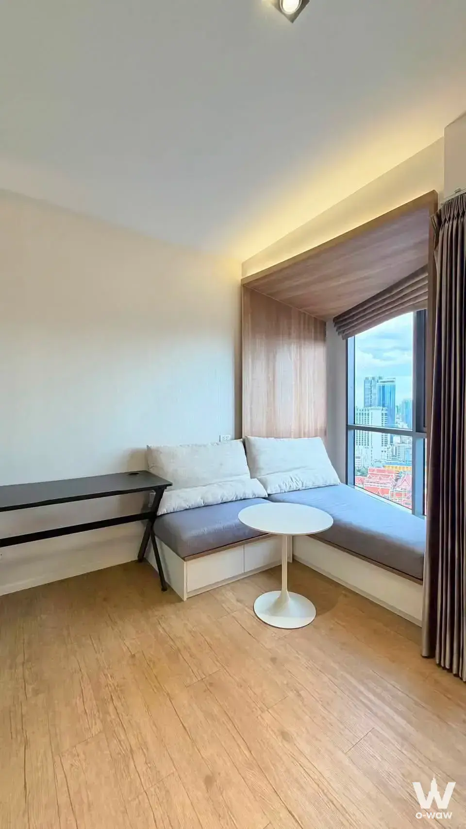 Built-in window seat with grey cushions and skyline view in this minimalist 1-bed condo at Triple Y Residence