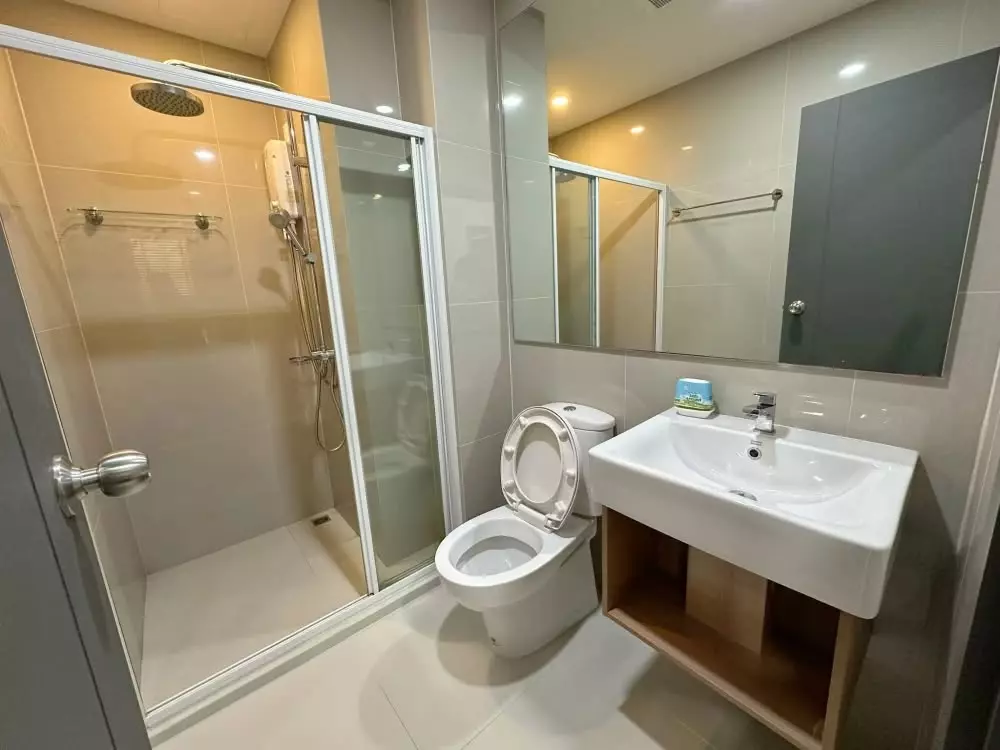 ELIO DEL NEST bathroom with beige tile walls, wooden vanity, and glass shower enclosure