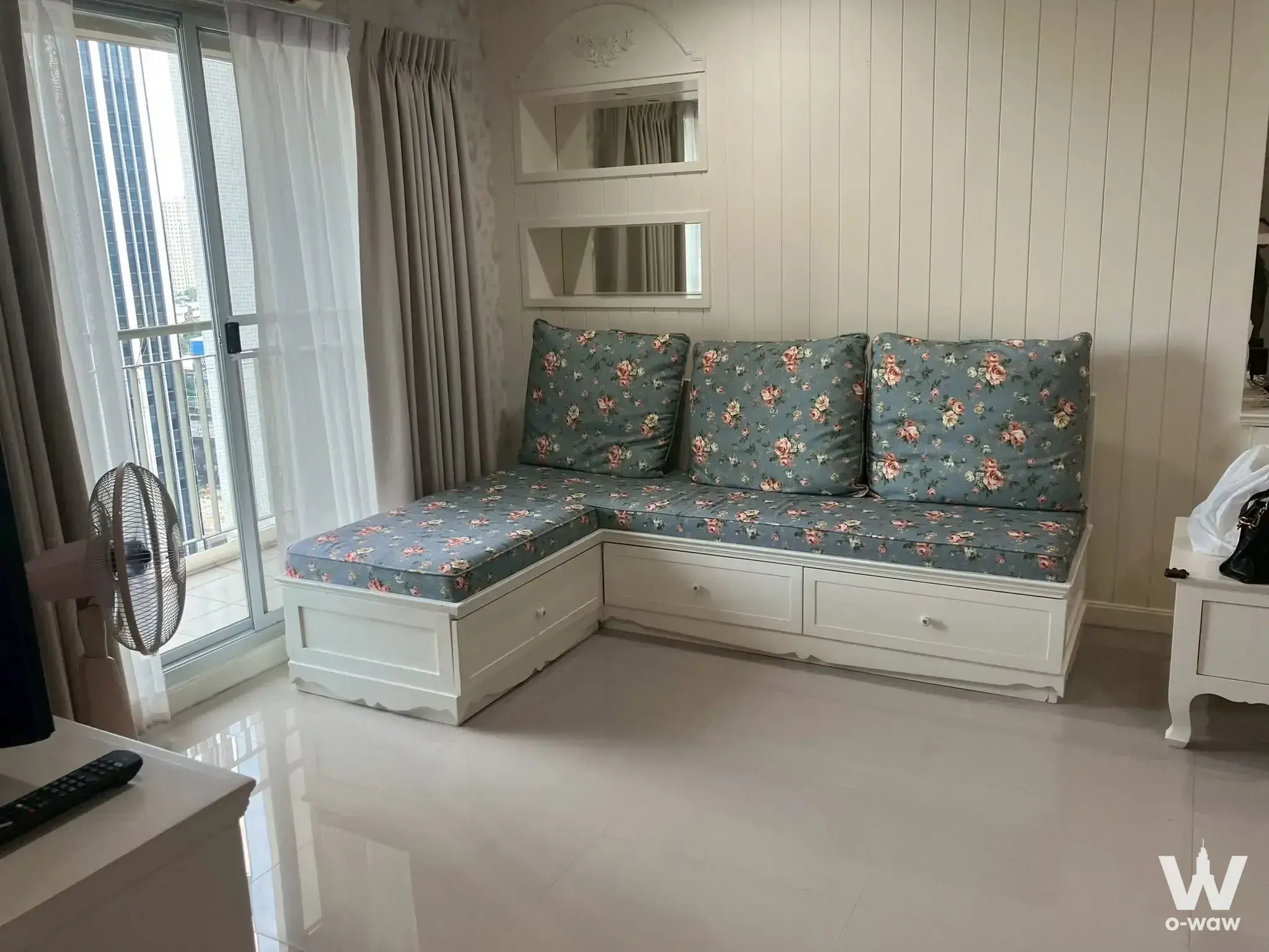 Living room with sectional sofa and balcony access in a 1-bed condo for rent in Lumpini Place Rama 8