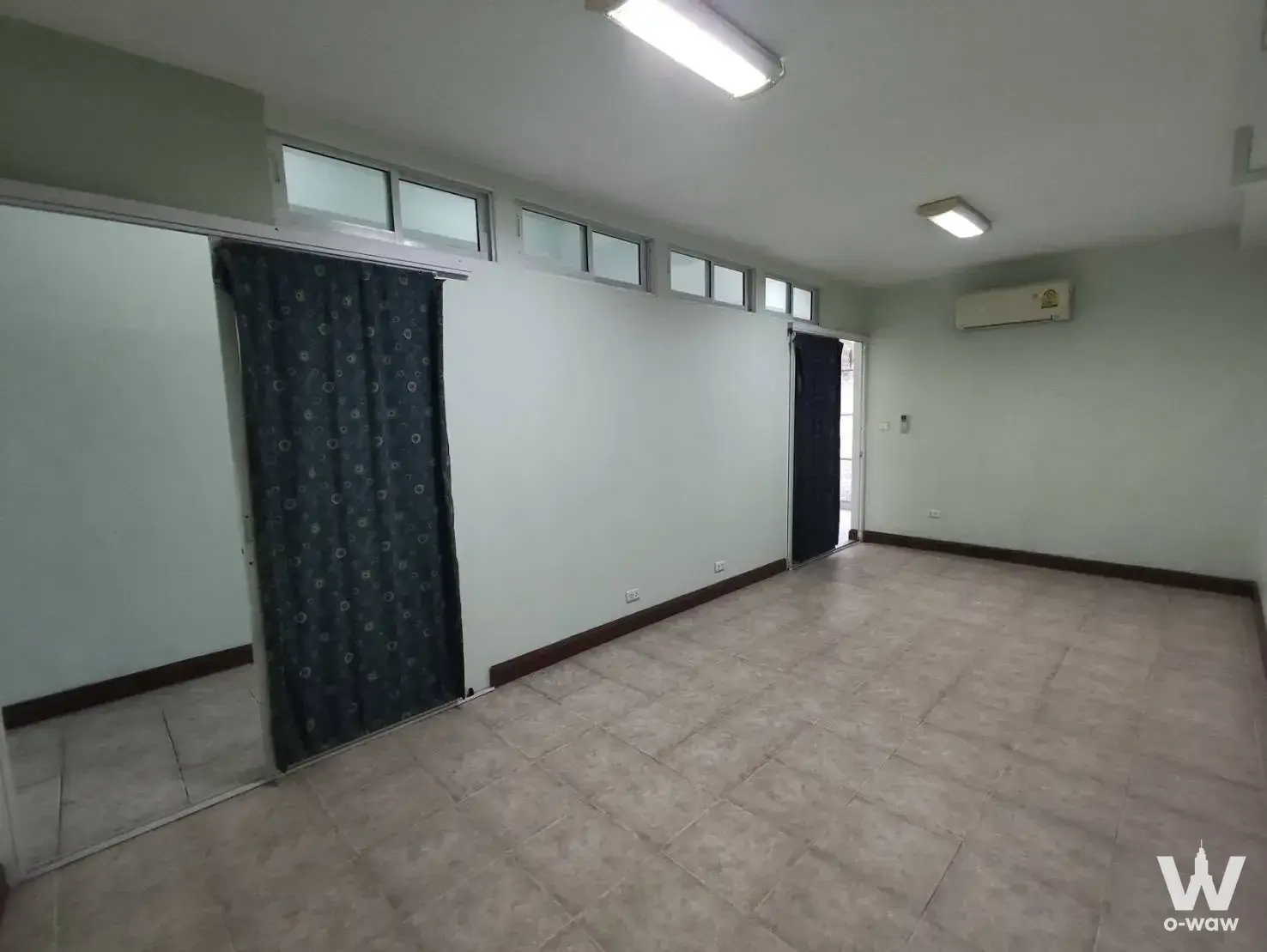 This Sukhapiban 3 condo room for sale has mint-green walls, beige tile floor and high transom windows