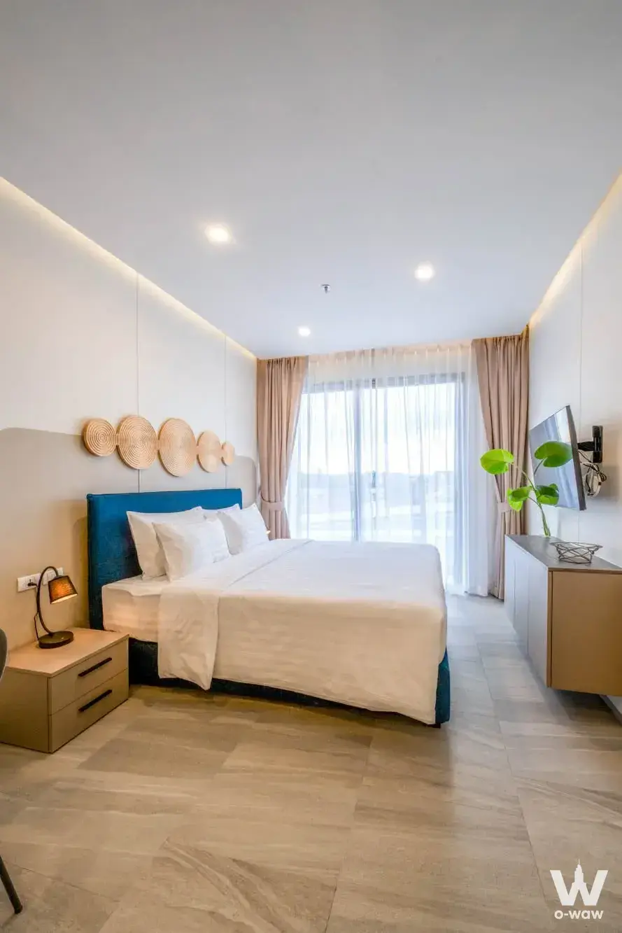 Blue upholstered bed and balcony access in a modern bedroom at HOMA Cherngtalay