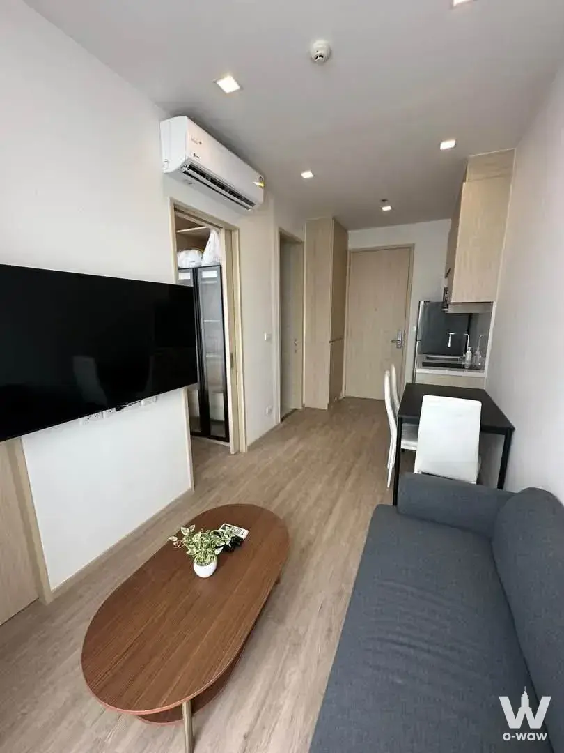 Furnished Noble State 39 living area featuring light wood floors, black TV, and kitchenette