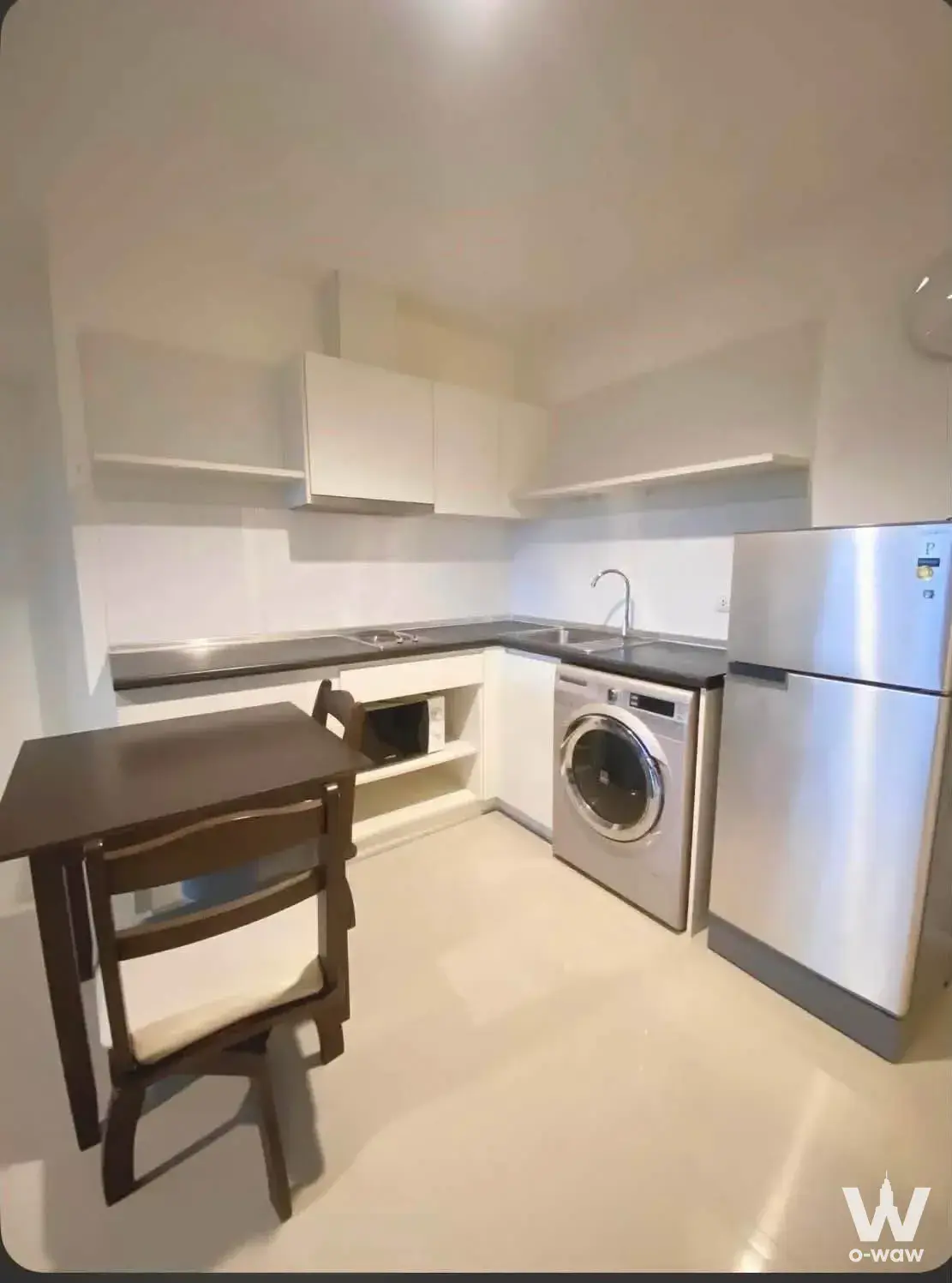 L-shaped kitchen with white cabinets and dark countertops in a 2-bed Aspire Sukhumvit 48 condo
