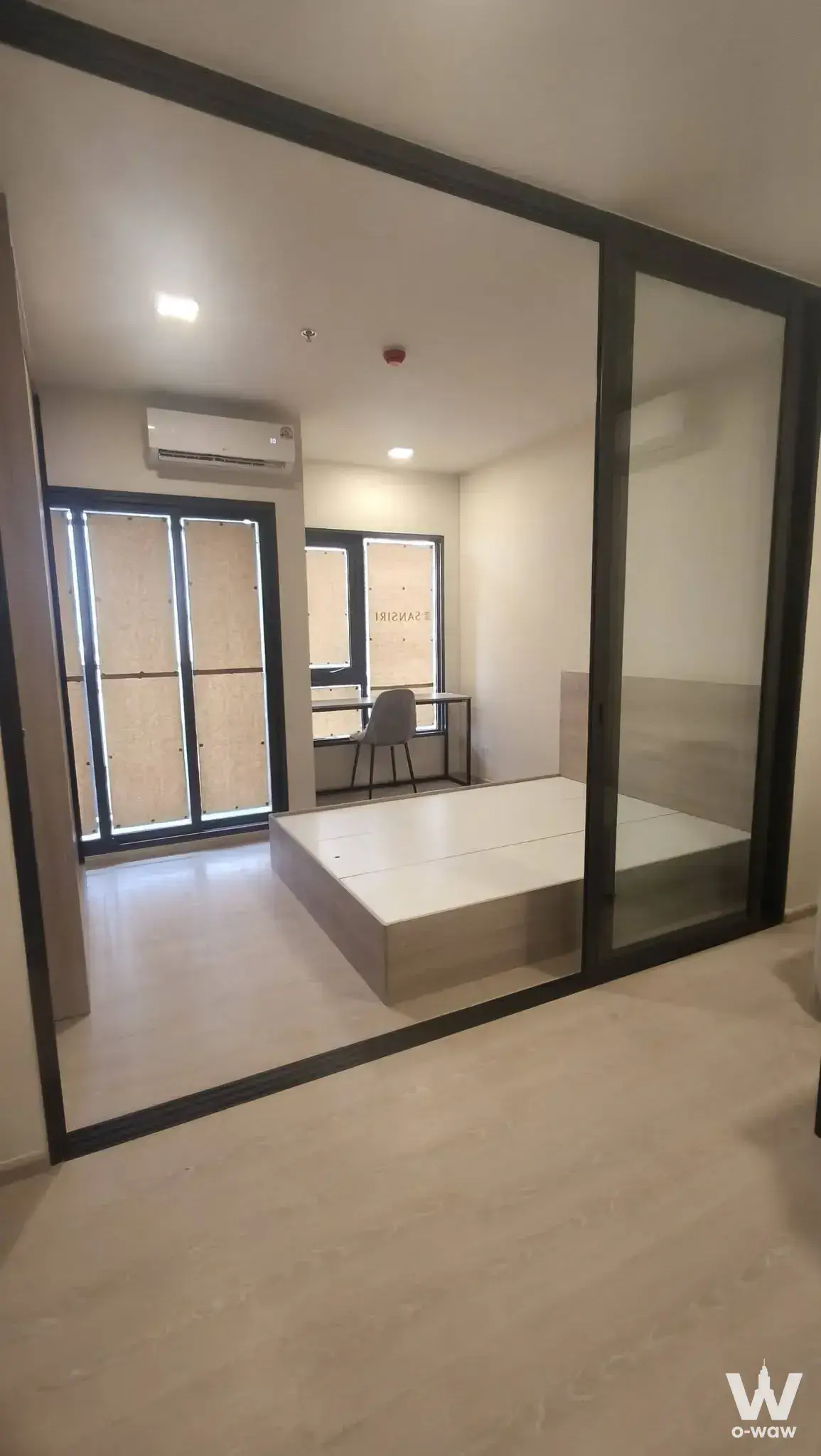 Minimalist bedroom in FLO by Sansiri with a platform bed and black metal frame partitions during renovation phase