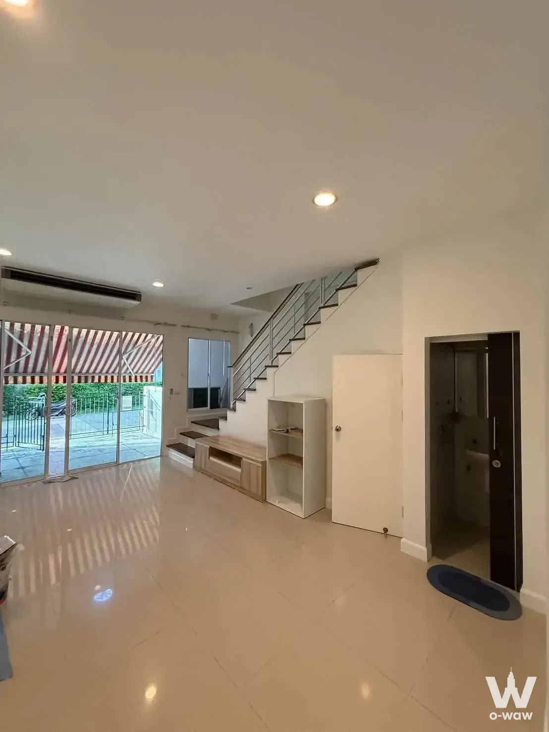 Ground-floor living area in Ban Klang townhouse Sathorn-Taksin 2 with glossy tile floor and stairs