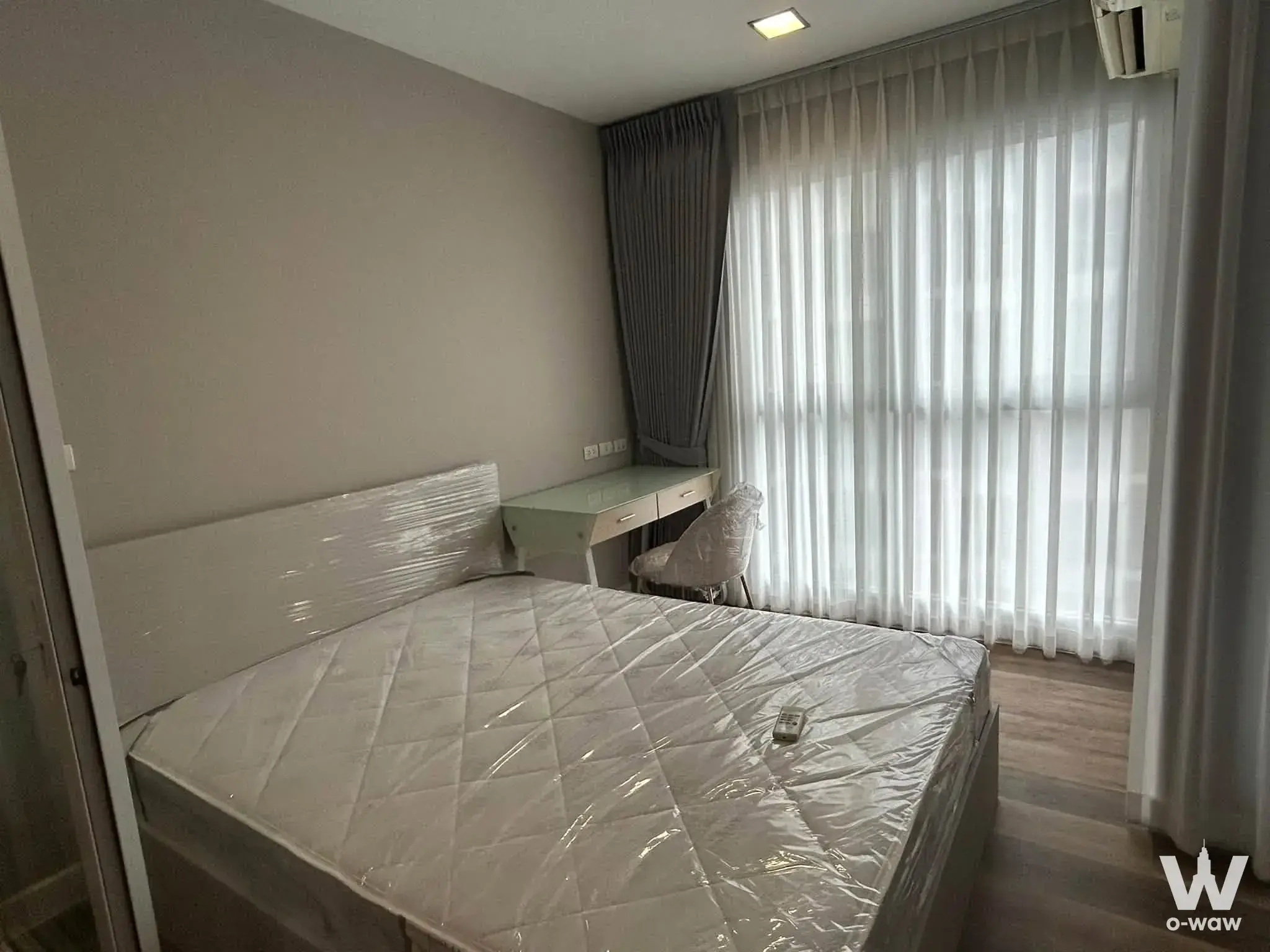1-bed condo for rent in CU Terrace showing a new unfurnished bedroom with plastic-wrapped bed and light wood laminate floor