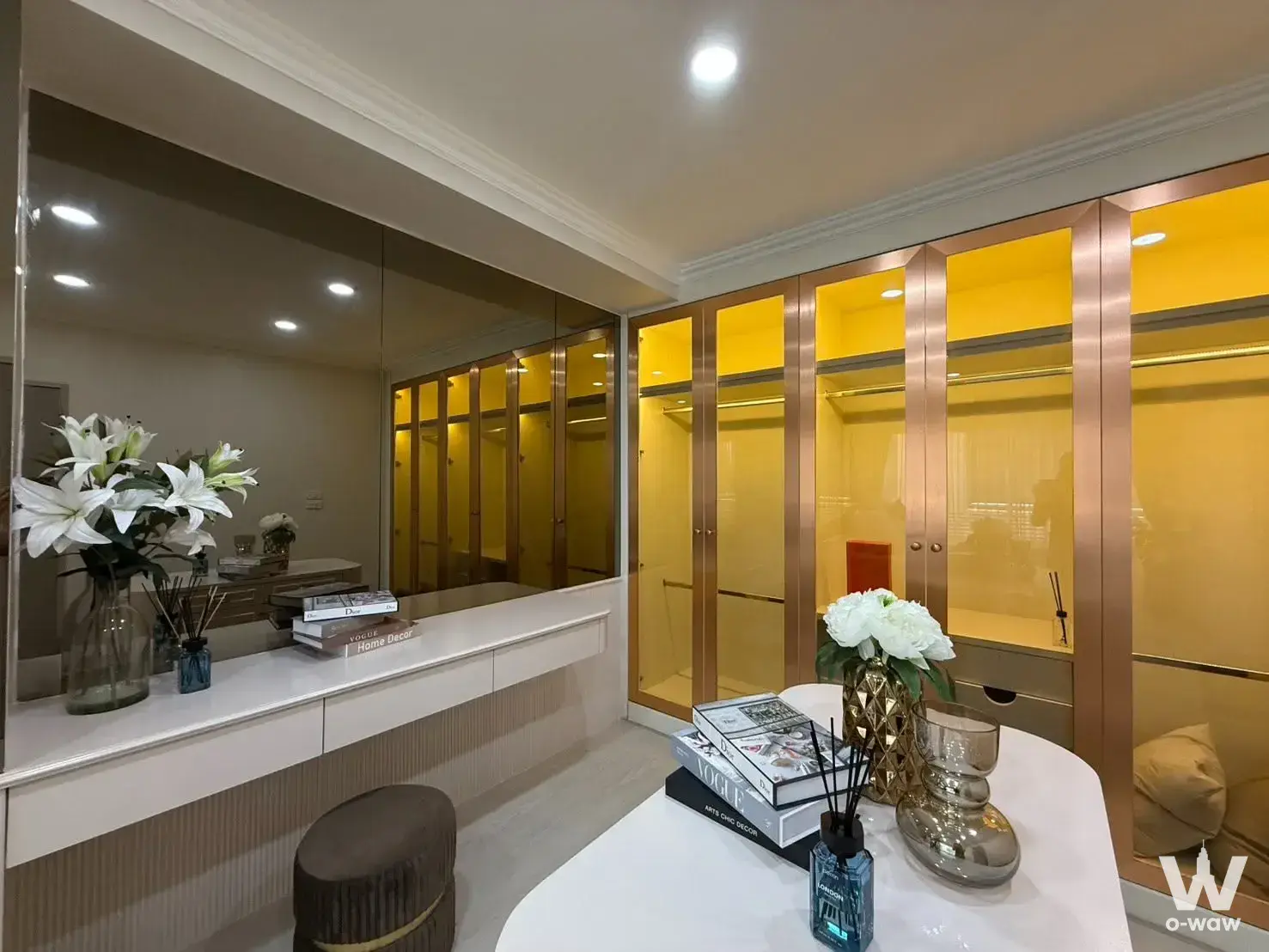 Walk-in closet in a 2-bed Saranjai Mansion condo with floor-to-ceiling amber glass wardrobes and a white vanity