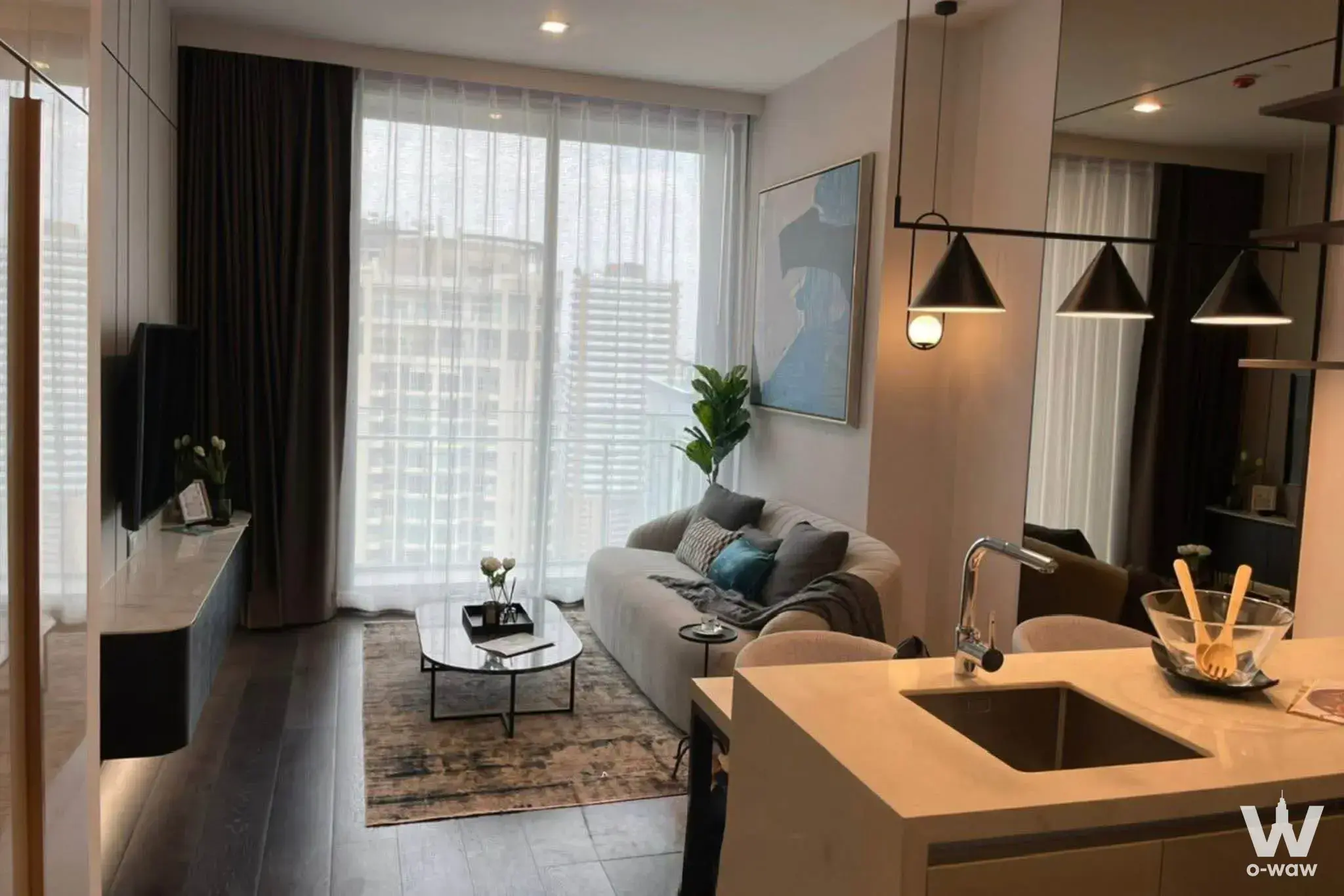 The open-plan living room and kitchen in this 1-bed LAVIQ Sukhumvit 57 rental has a grey sofa, stone island and city view