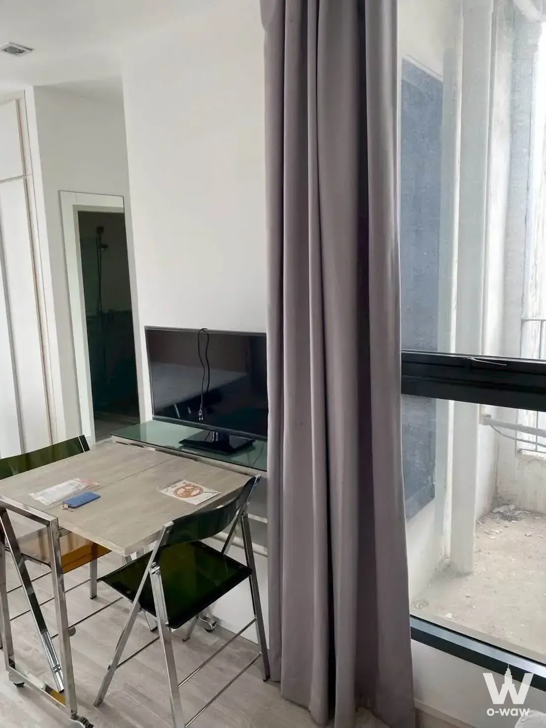 Studio living area in a 1-bed Ideo Mobi Sathorn rental with a small dining set and glass balcony door