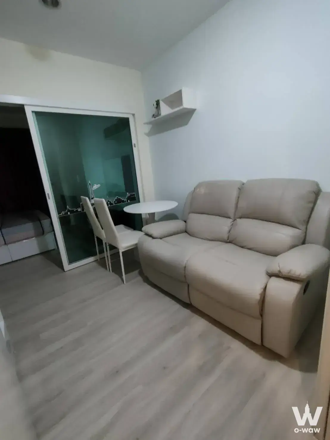 1-bed condo for rent in Aspire Sathorn featuring a living room with beige leather sofa and sliding glass partition