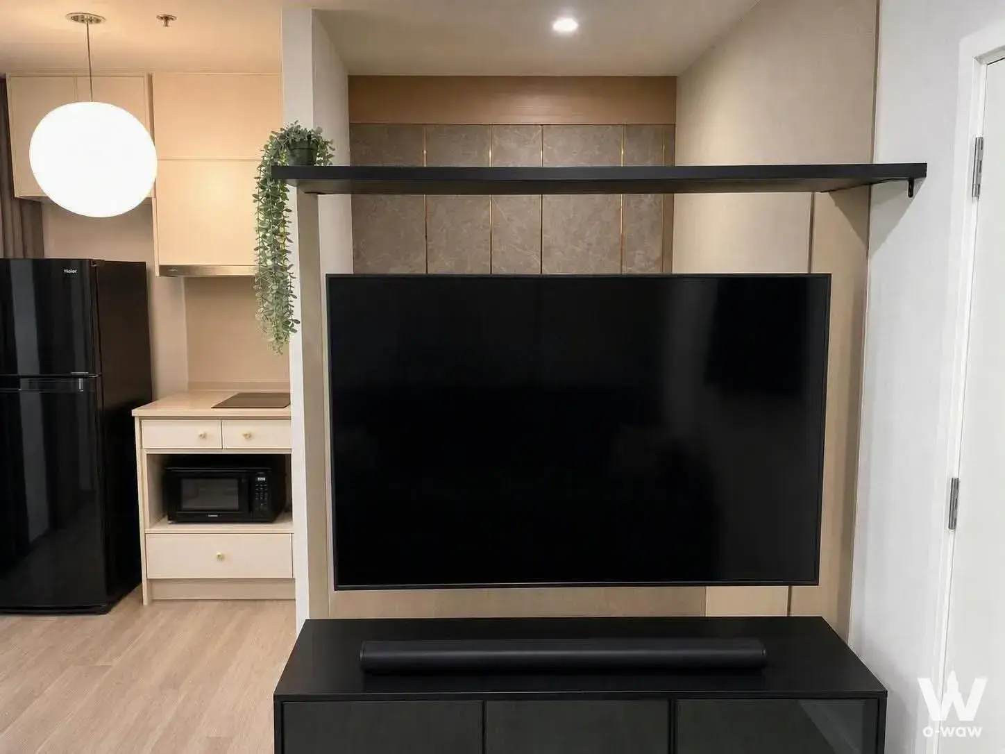 Open-plan living area in a 1-bed condo at The Privacy Rama 9 featuring a wall-mounted TV and kitchenette
