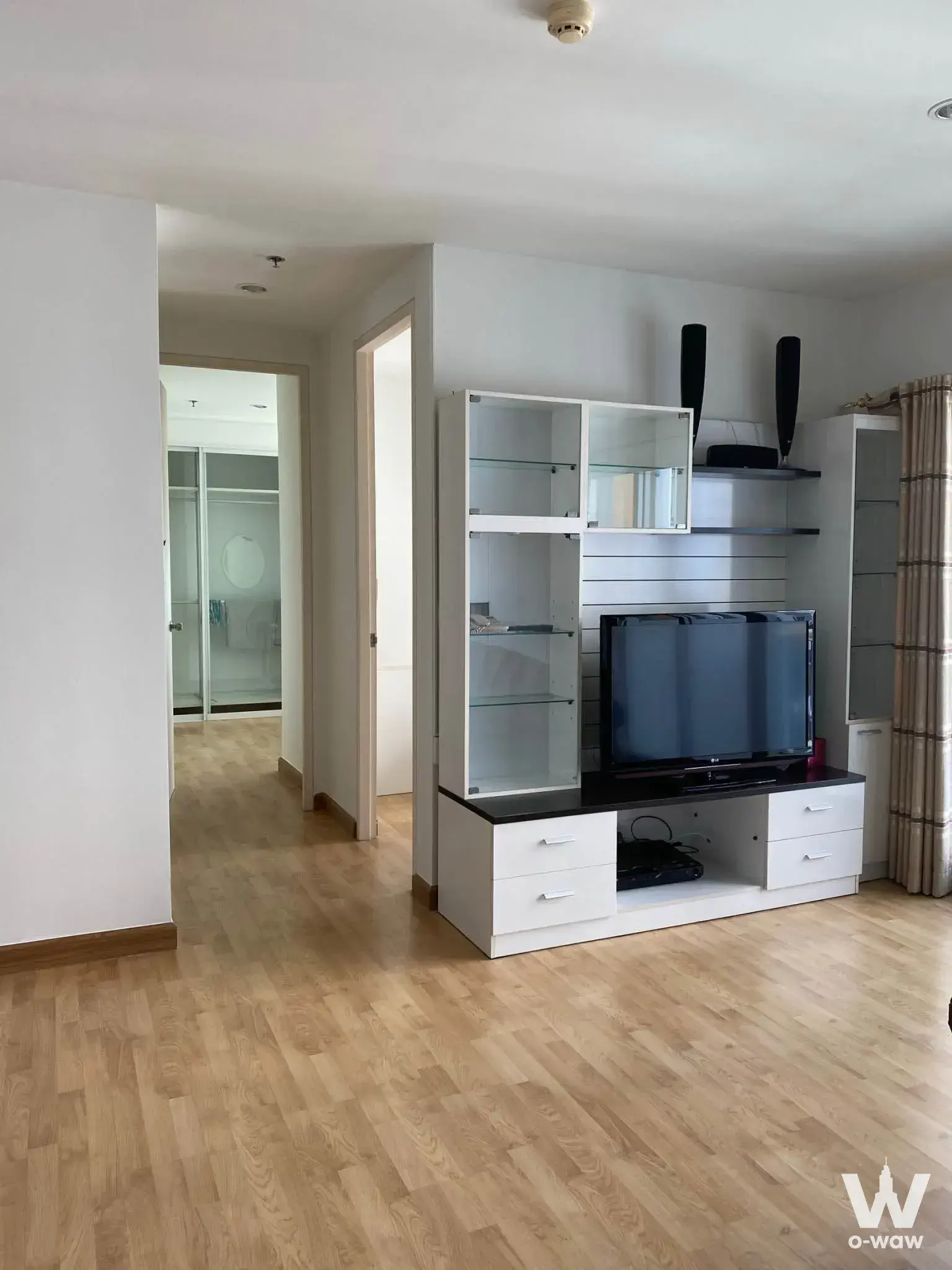 Bright living room in a 2-bed condo for rent at The Parkland Taksin, Tha Phra, with a white media unit and black TV