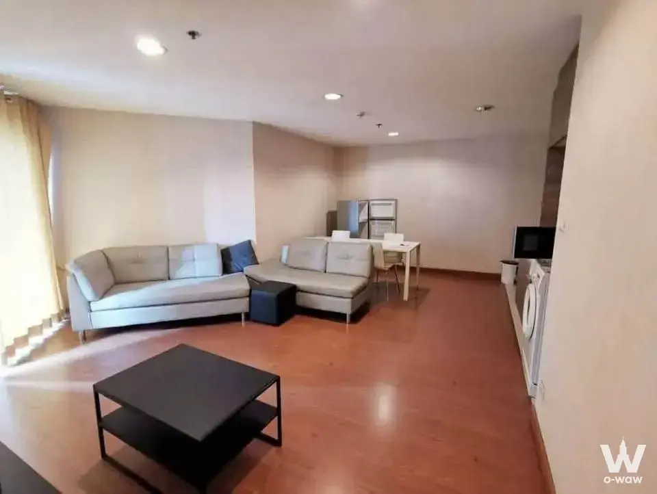 Bright open-plan living space in Belle Grand Rama 9 with L-shaped sectional sofa and compact dining nook
