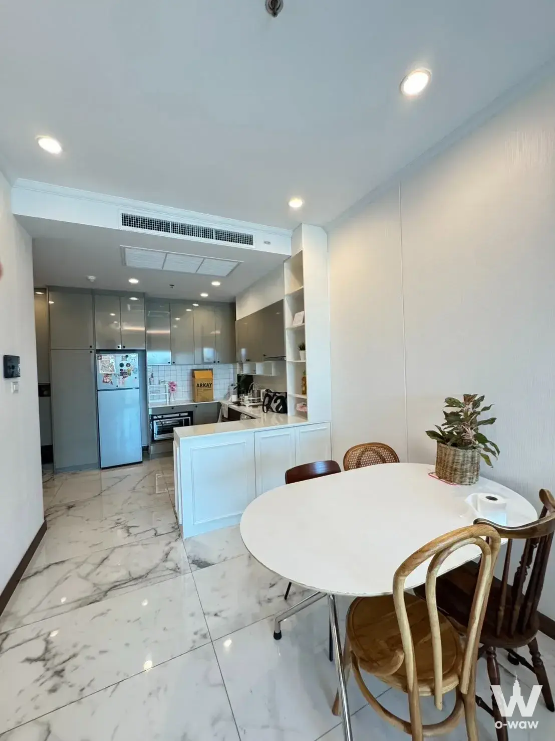 Open-plan dining and kitchen in Supalai Elite Surawong condo with white cabinetry and marble floors