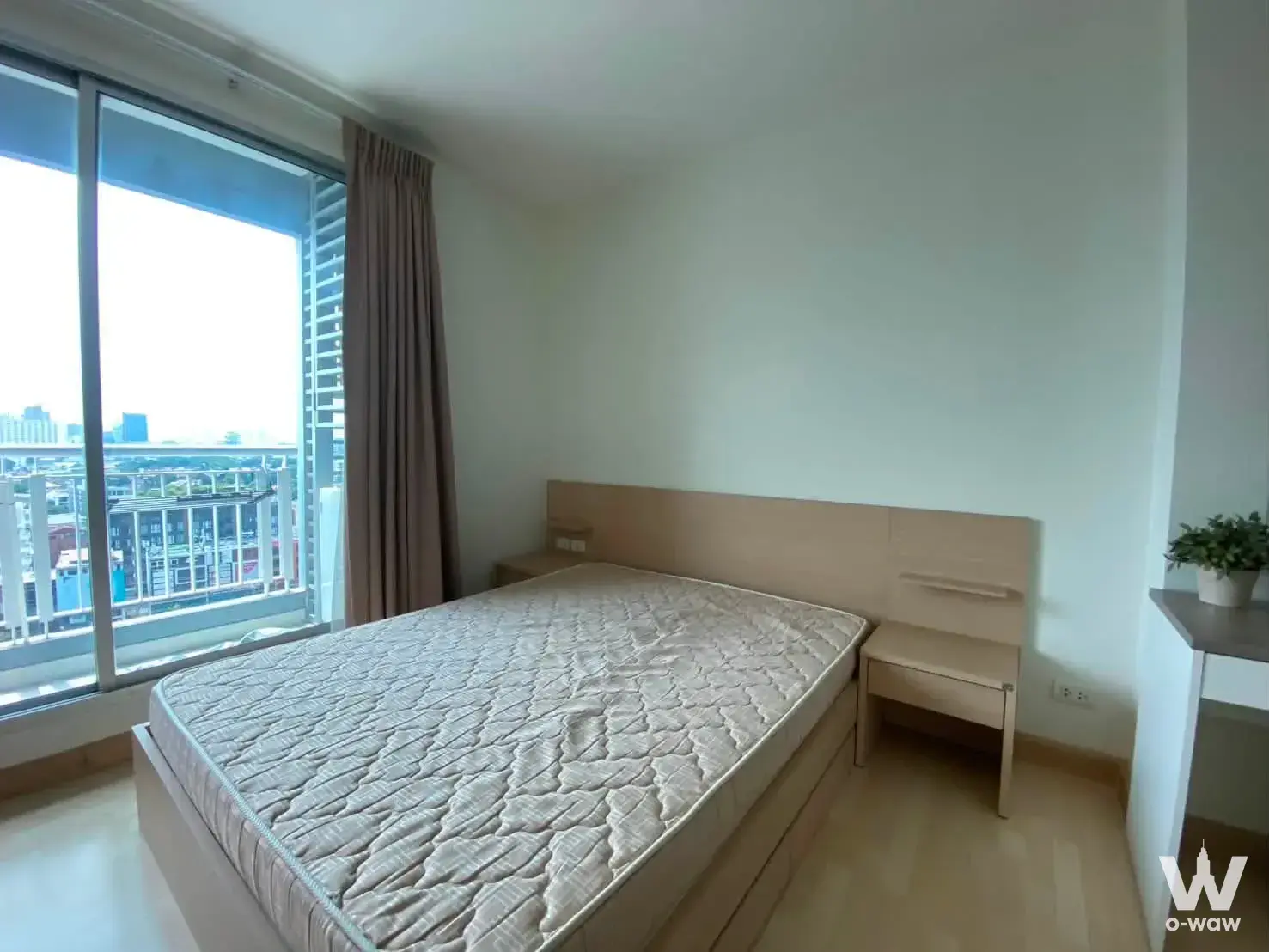 Queen bed with light wood storage base and built-in headboard in a 1-bed condo for rent at RHYTHM Ratchada